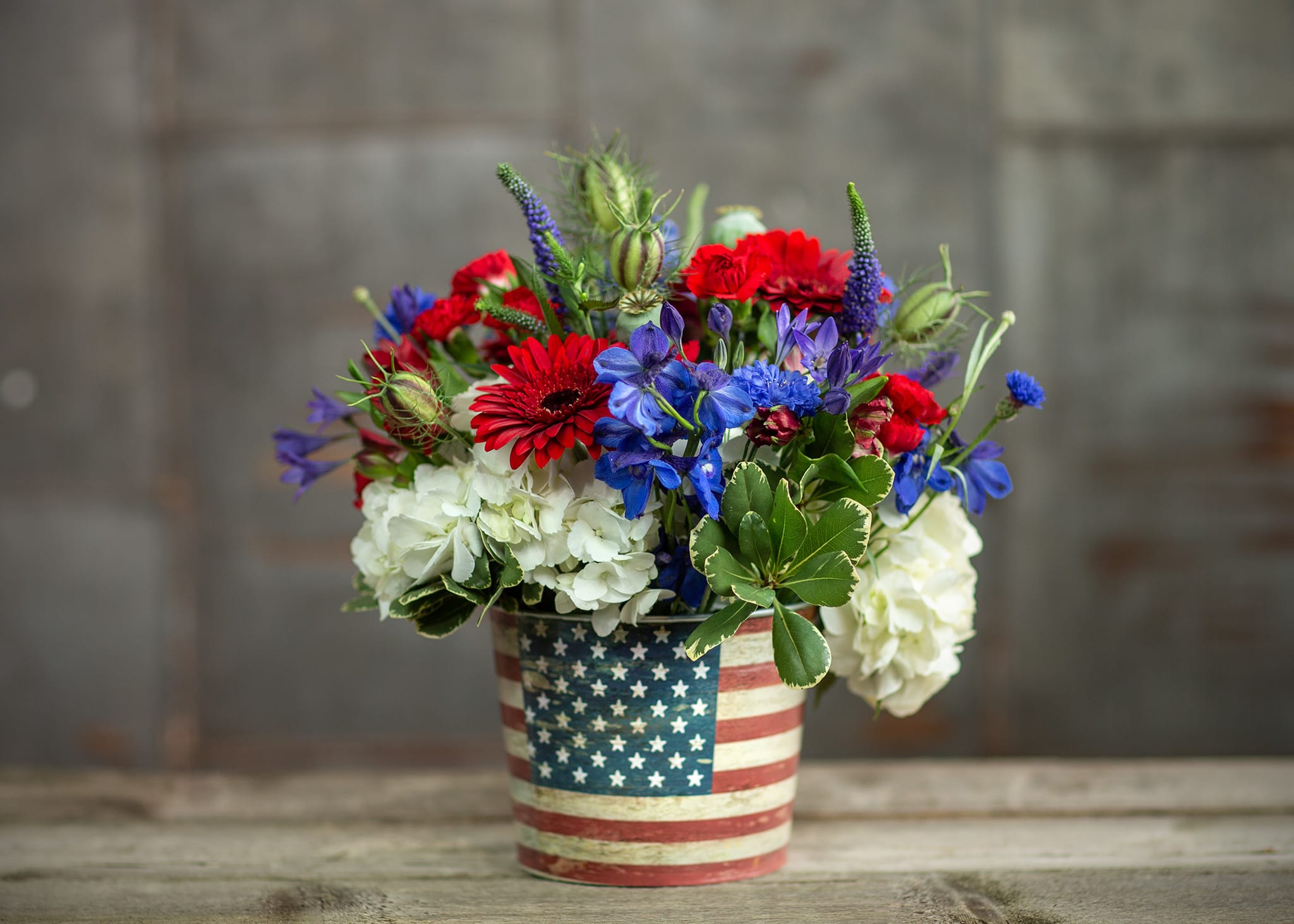 Red, blue, and white flowers in an American flag tin container
