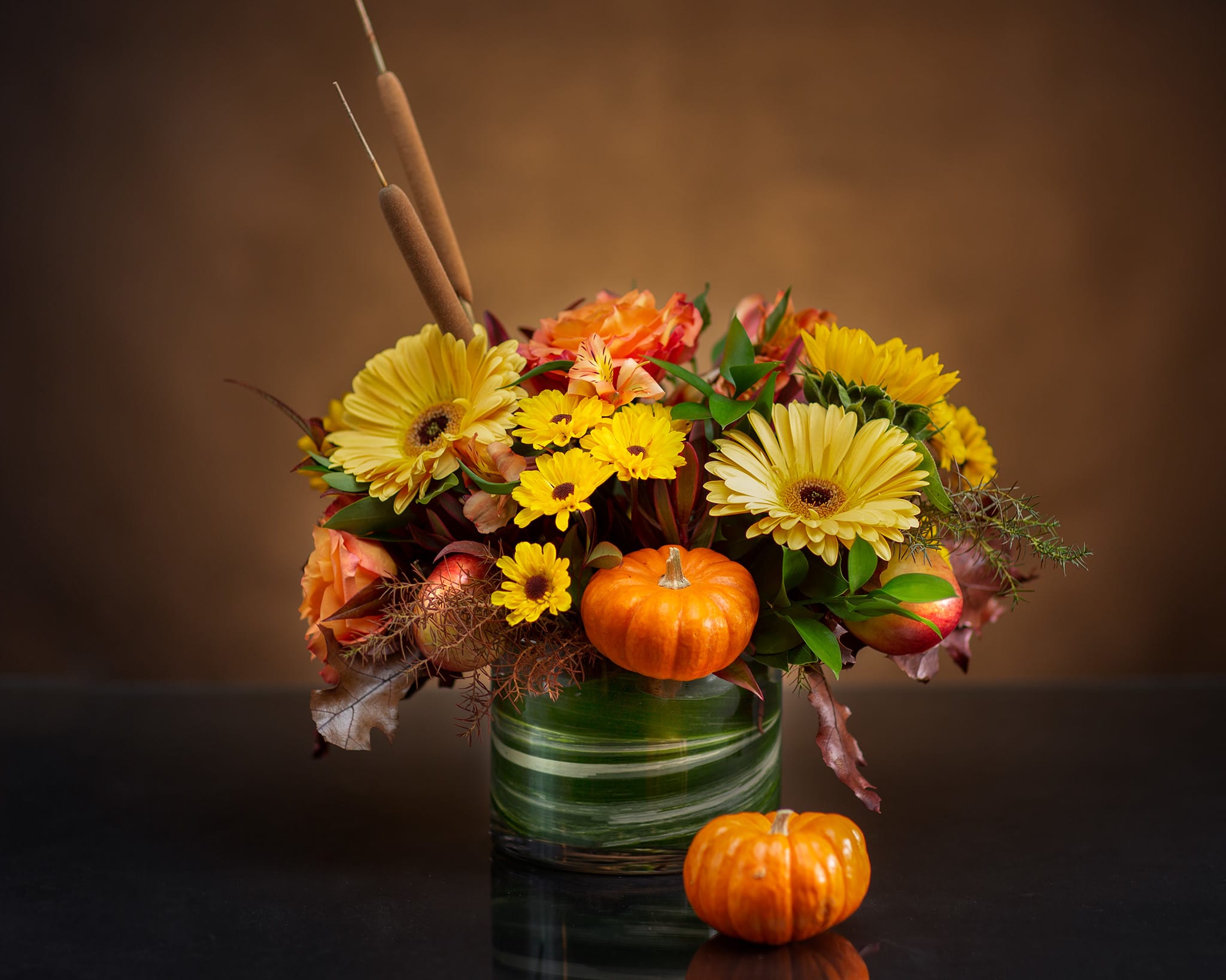Autumn bouquet with yellow daisies and orange roses in a glass vase