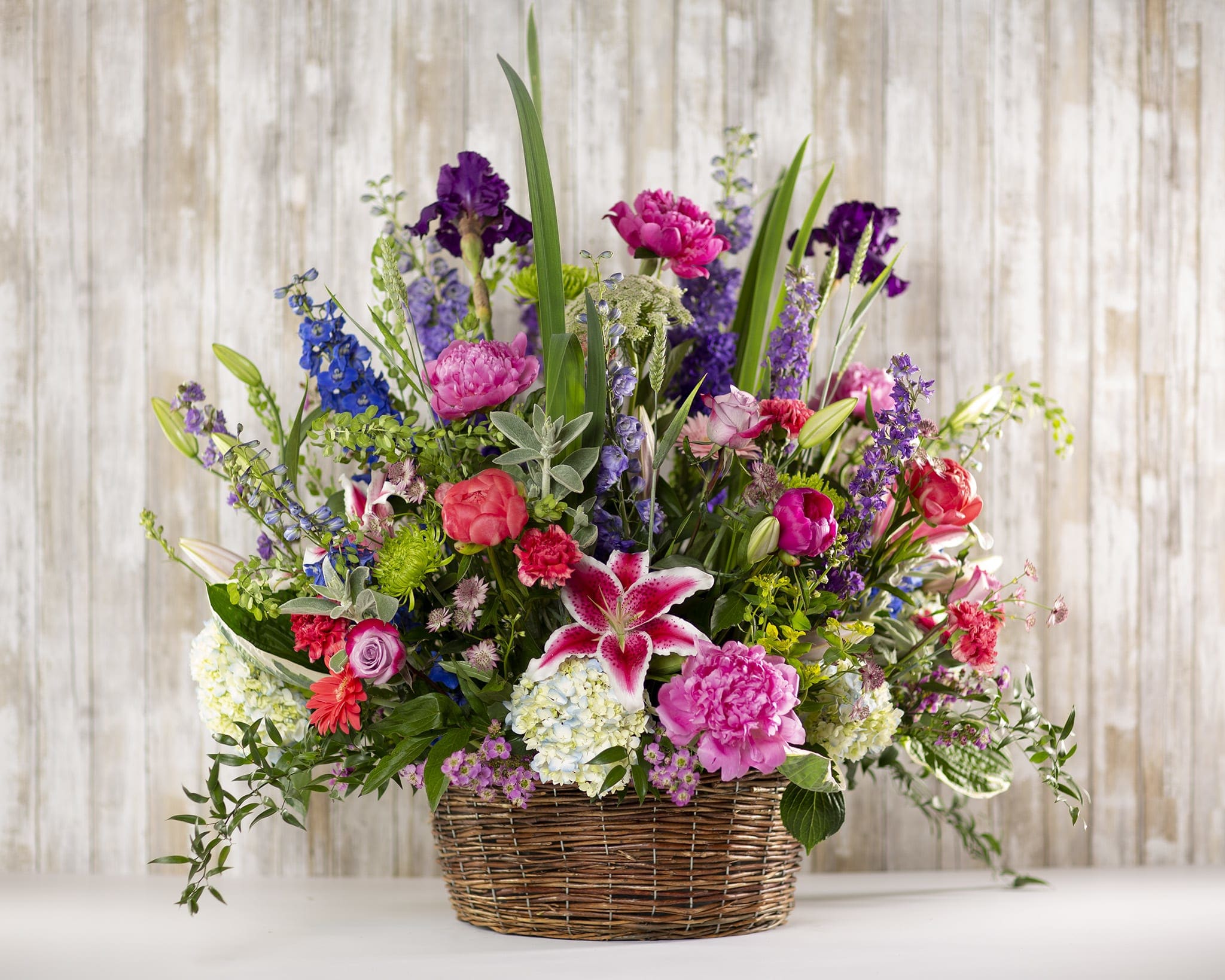 Mixed bouquet in a wicker basket with pink, purple, and white flowers