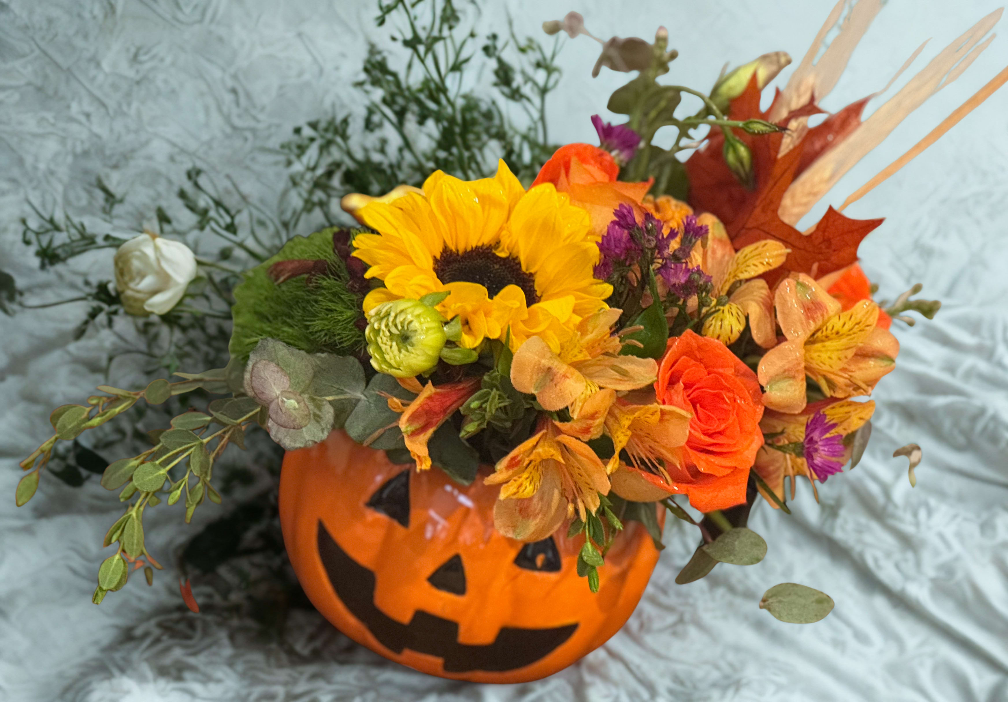 Fall Pumpkin Arrrangement - Fall flowers including sunflowers, filler flower, orange roses, alstroemeria, fall leaves, wheat sprigs, trick dianthus and greenery fill this adorable ceramic pumpkin container. Long lasting and beautiful. 