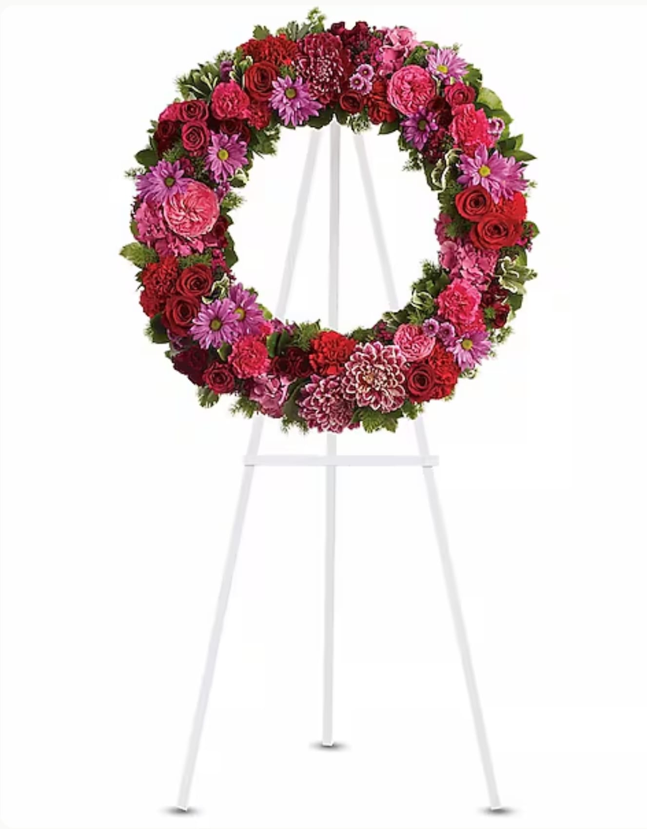 Circular floral wreath on a white easel with red, pink, and purple blooms