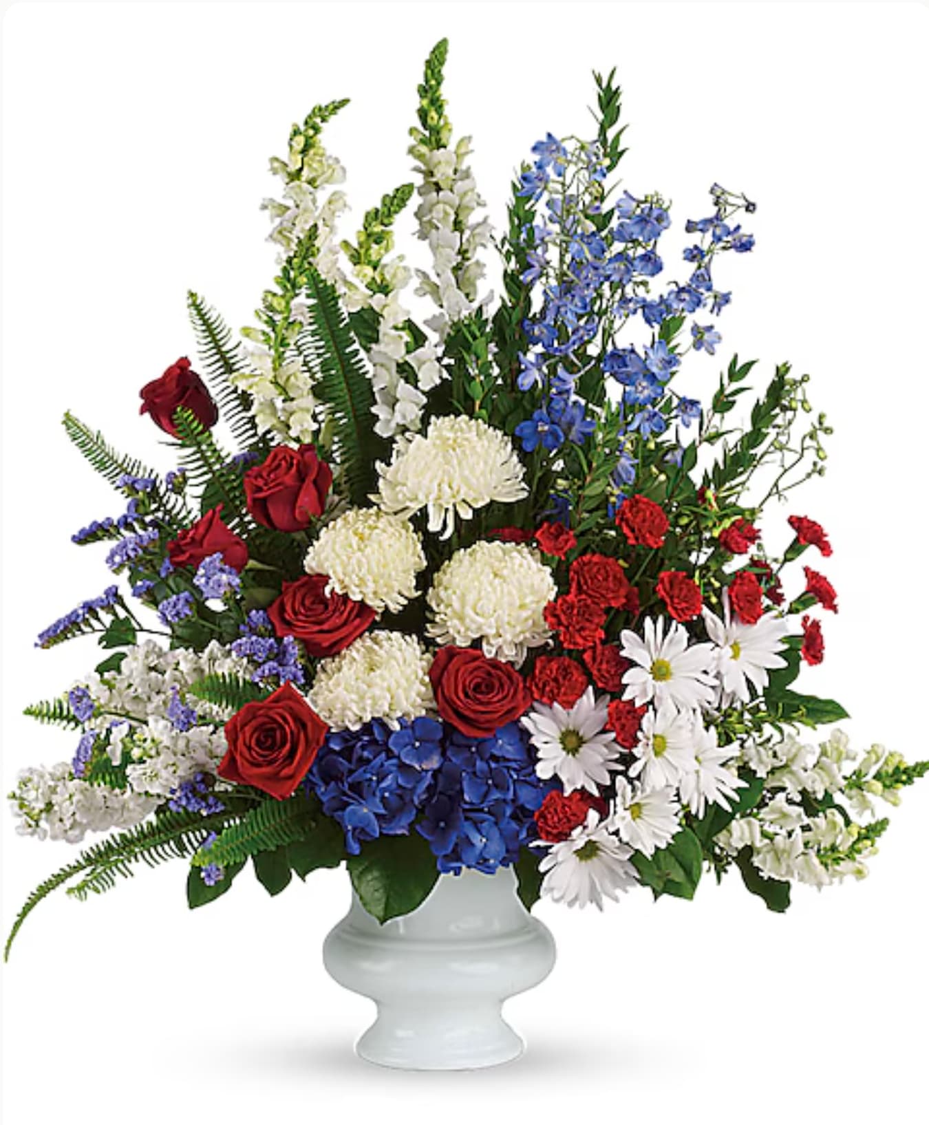Mixed red, white, and blue floral arrangement in a white pedestal vase