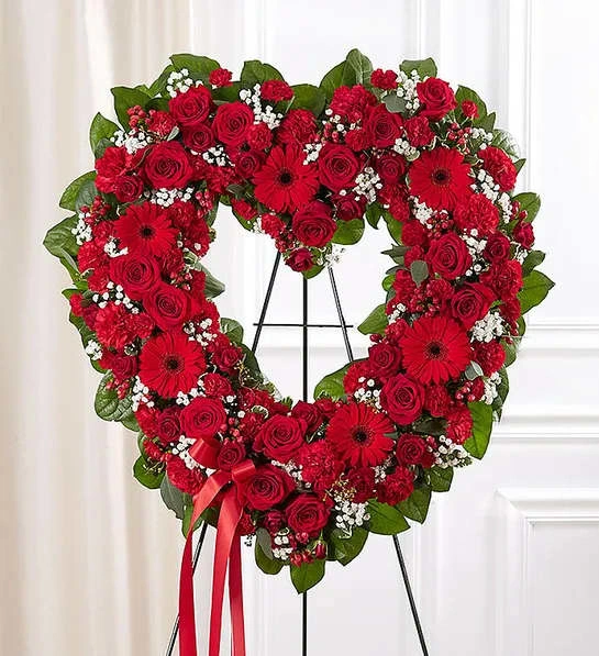Floral Heart Tribute- Red - The love for someone who has passed away lives on forever in the hearts of those left behind. This sentiment is best captured with our standing, open heart-shaped red floral arrangement. Handcrafted by our caring florists with an assortment of radiant red blooms, it is a magnificent tribute fitting for the funeral services.All-red open heart-shaped arrangement of roses, spray roses, Gerbera daisies, carnations, mini carnations, hypericum; accented with baby’s breath and soft, lush greenery