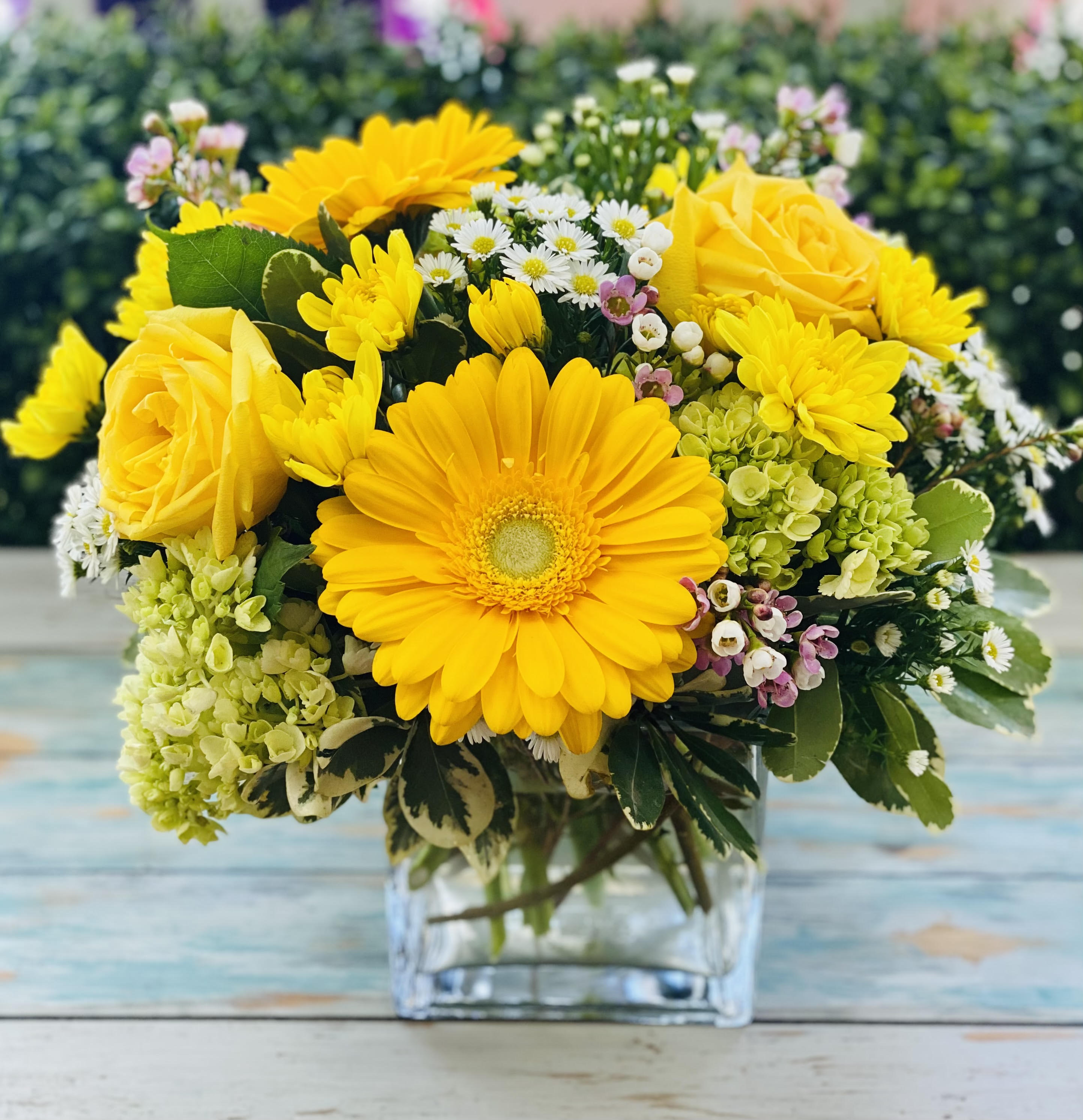 Yellow roses and daisies arranged in a clear glass vase
