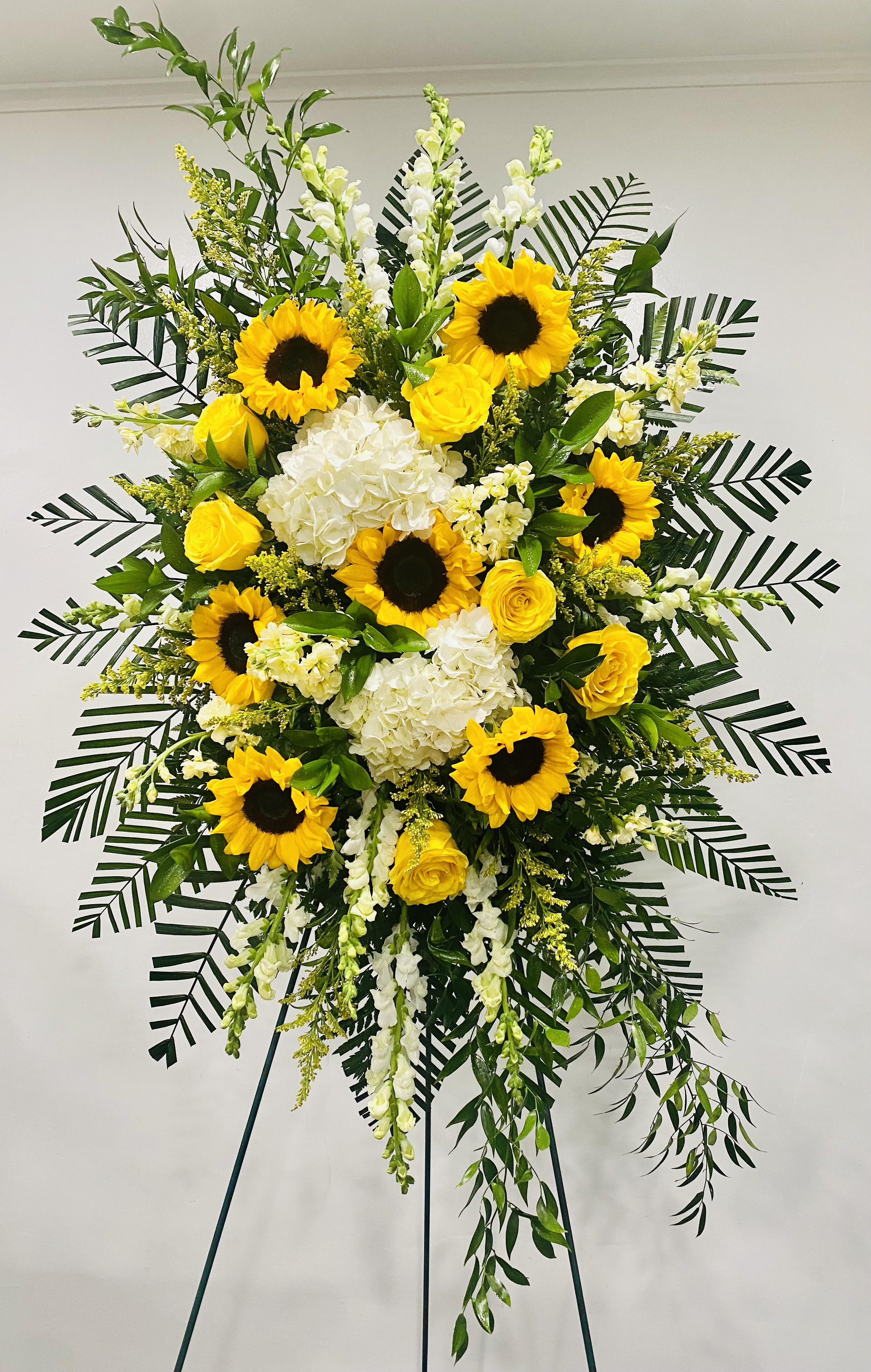 Tall standing floral spray with sunflowers, yellow roses, and white blooms