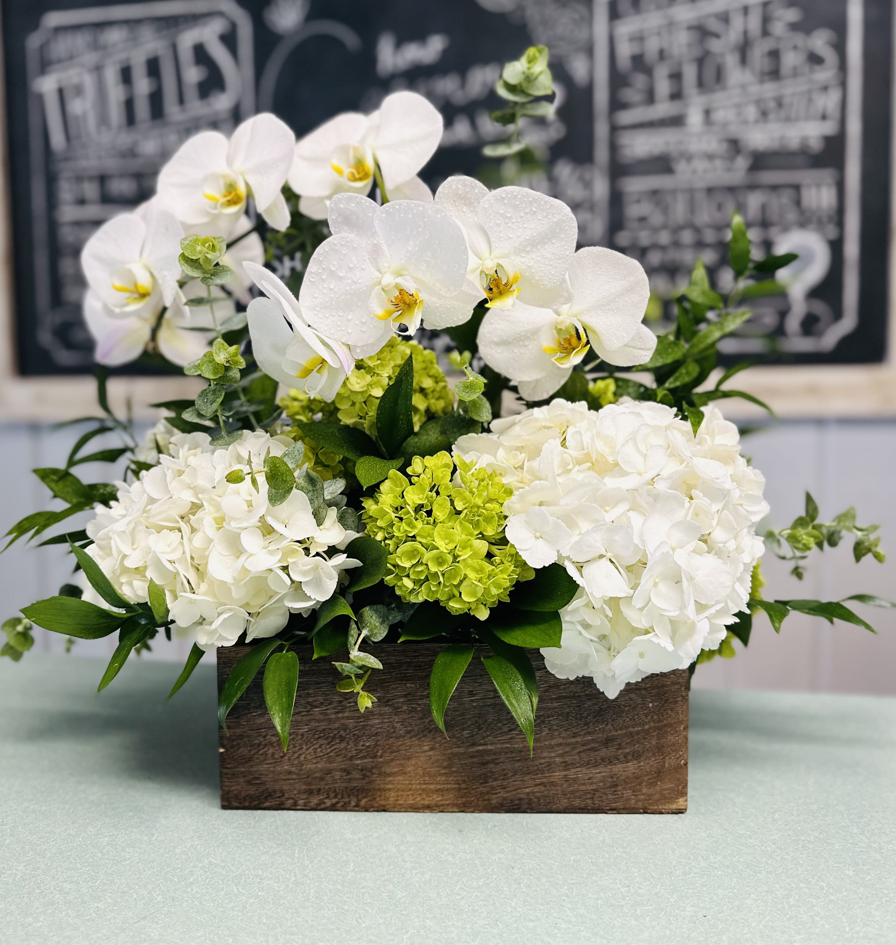 White orchids and hydrangeas in a wooden box arrangement