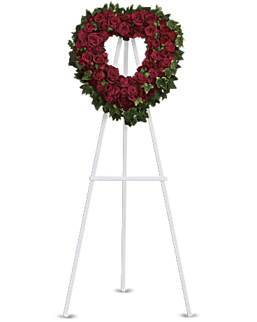 Heart-shaped red rose wreath on a white easel stand