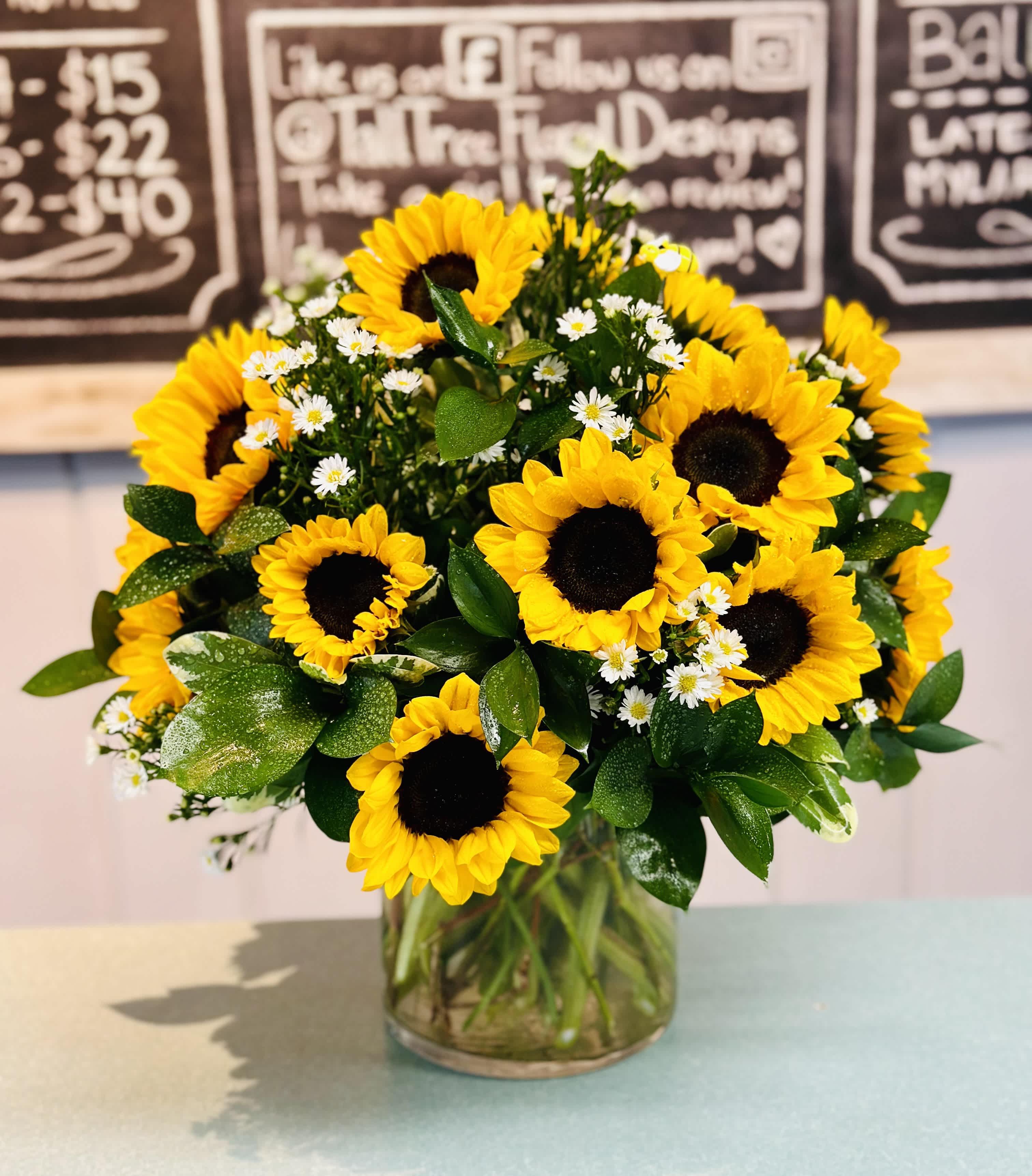 Bouquet of yellow sunflowers and small white daisies in a glass vase