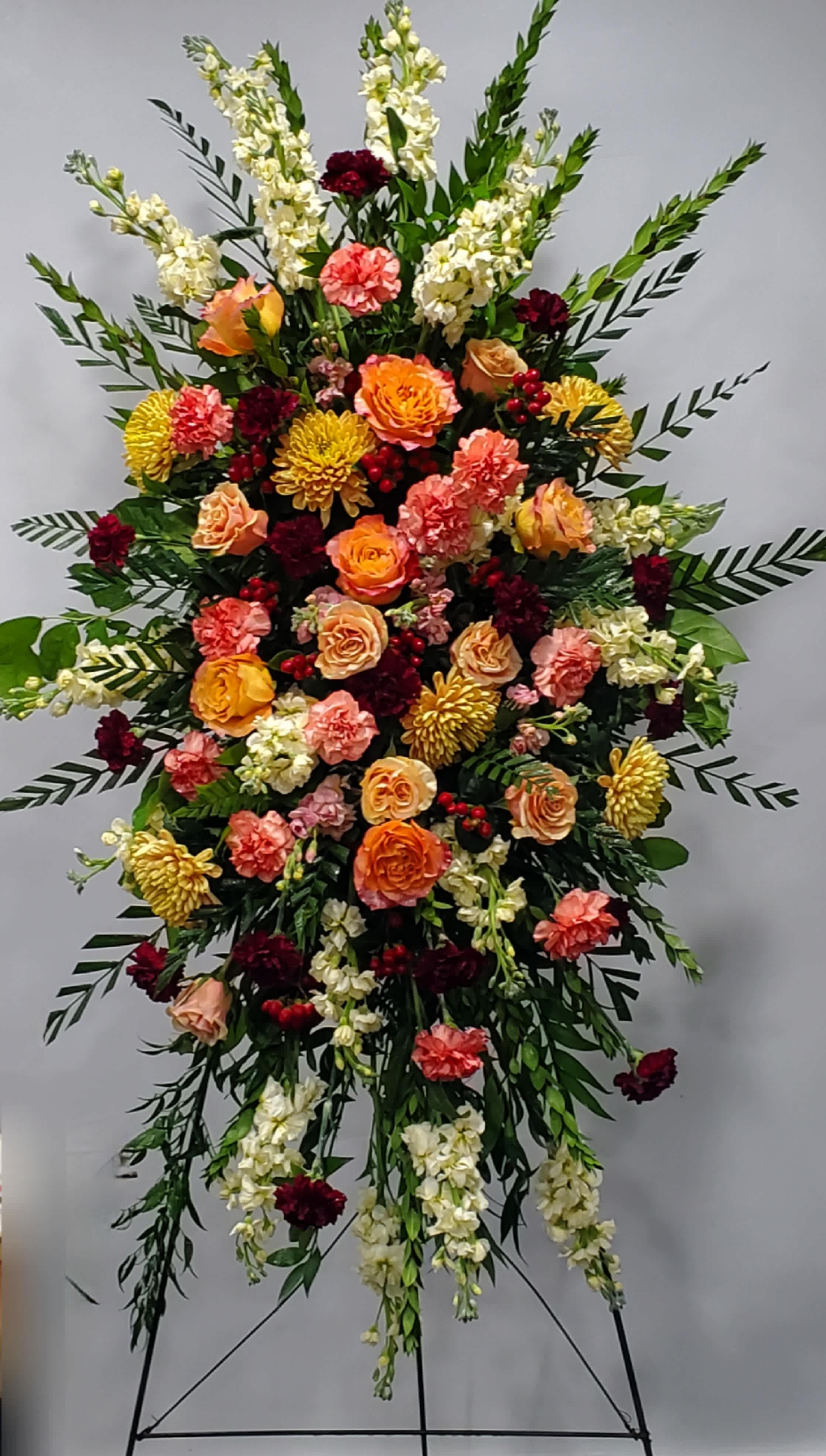 Large standing floral spray with roses, carnations, and white spikes