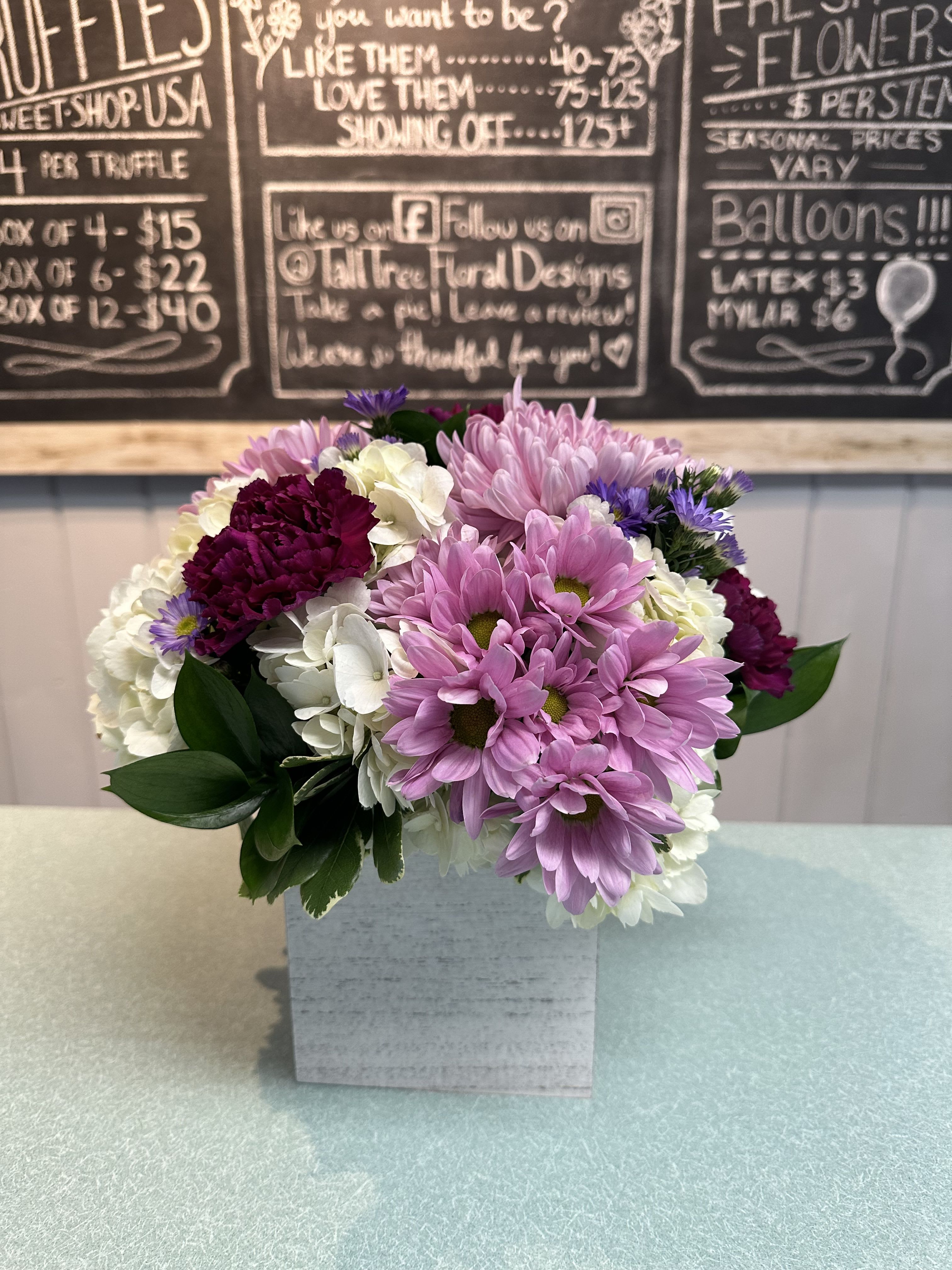 Pink and white daisy bouquet in a square white vase