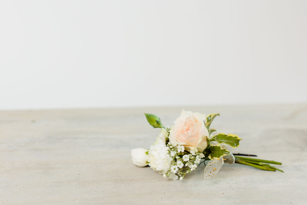 Small pale pink rose boutonniere with white flowers