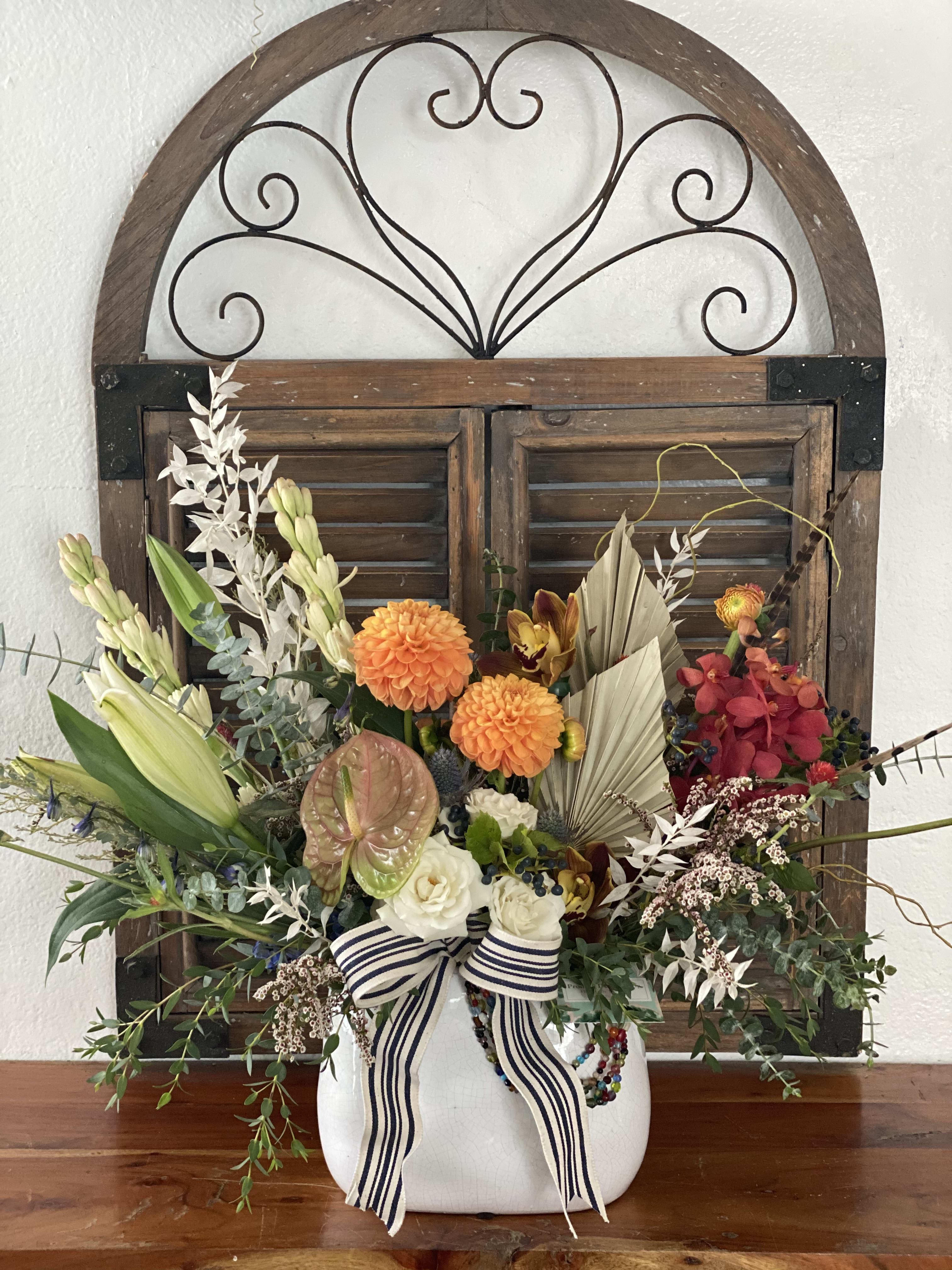 Colorful floral arrangement in a white vase with a striped ribbon