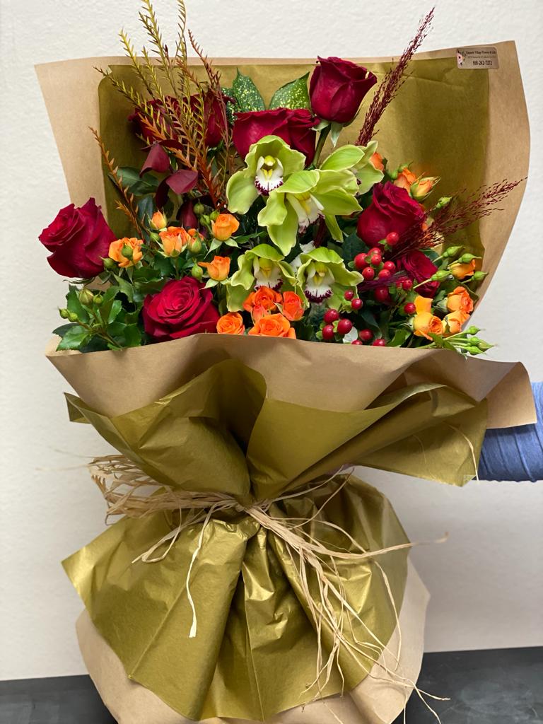 Bouquet of red roses and green orchids wrapped in gold paper