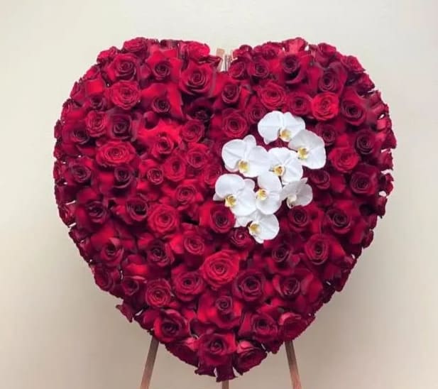 Heart-shaped arrangement of red roses with white orchids