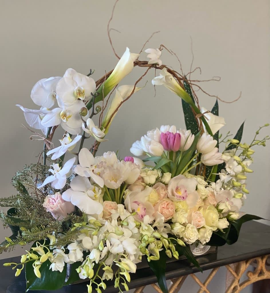 Large floral basket with white orchids, tulips, and pale roses