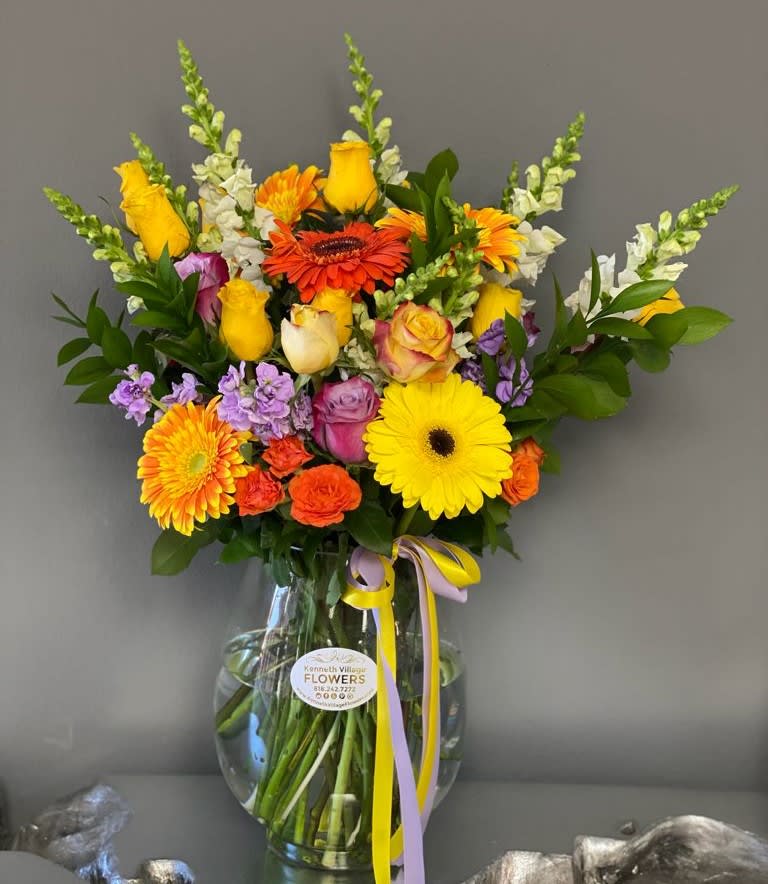 Colorful mixed bouquet in a clear glass vase with ribbon