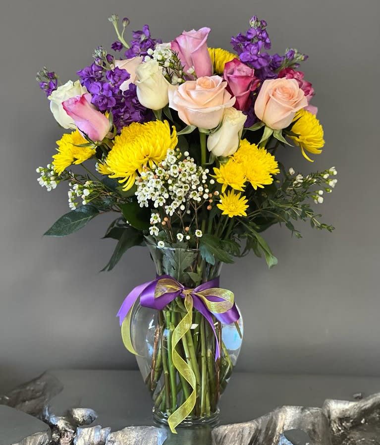 Mixed bouquet of roses and yellow chrysanthemums in a glass vase with ribbon