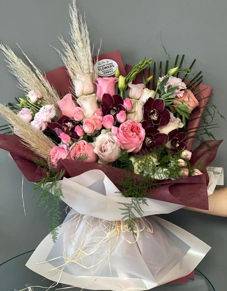 Bouquet of pink and burgundy roses with pampas grass and white wrap