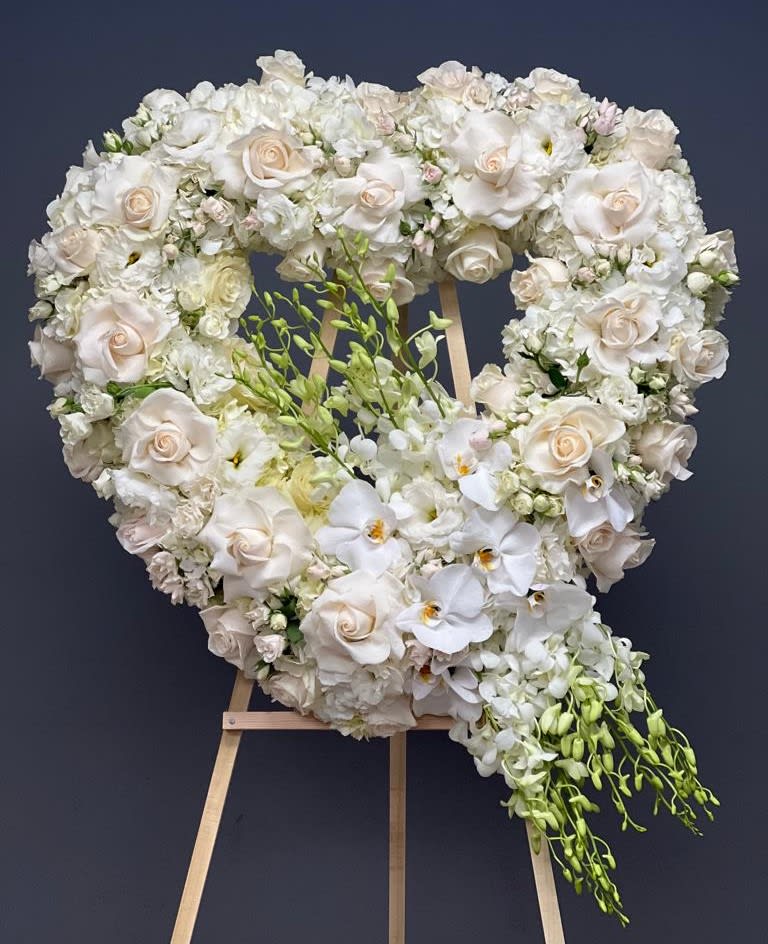Heart-shaped white floral wreath on a wooden easel
