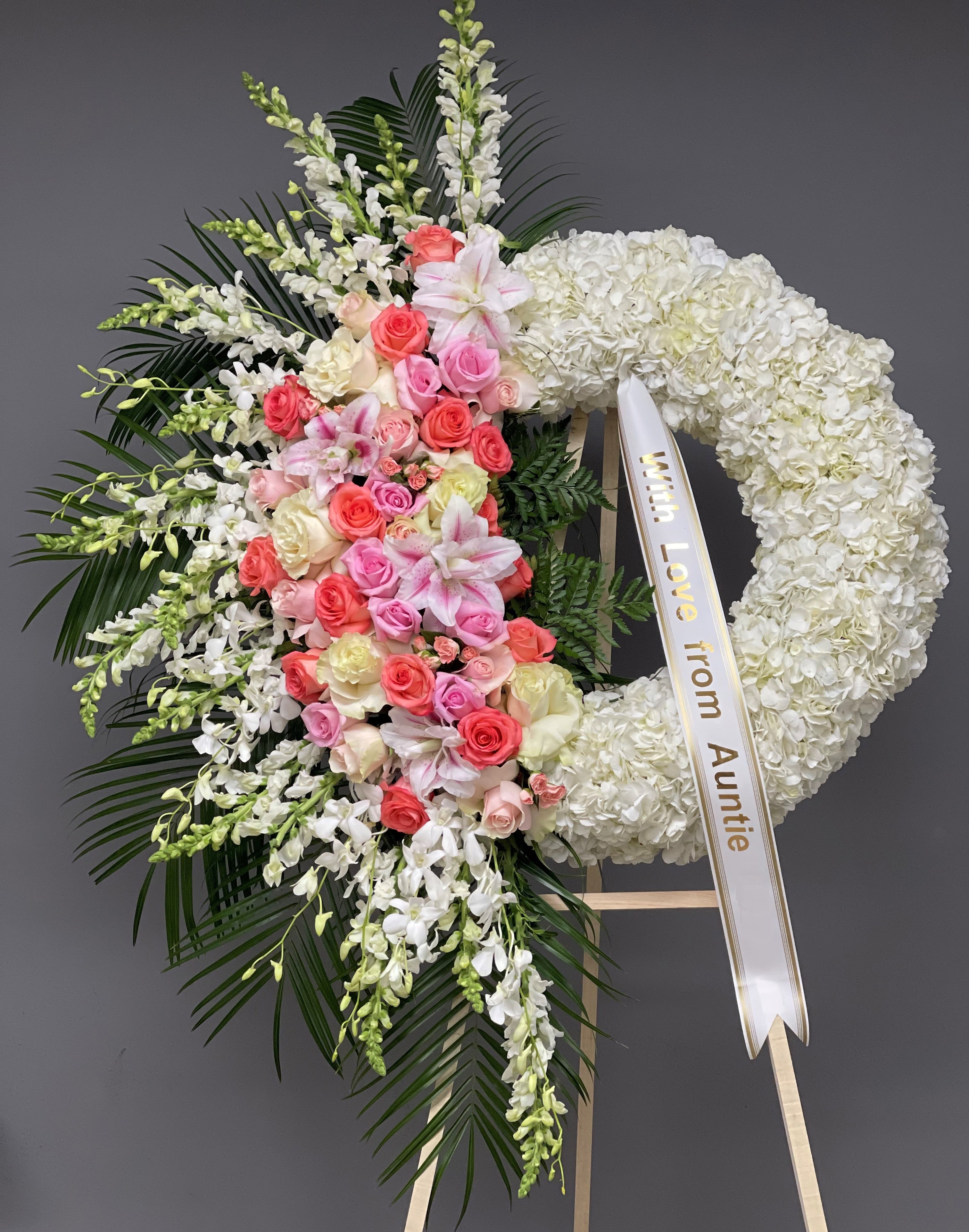 Heart-shaped floral wreath with pink and white flowers and a ribbon