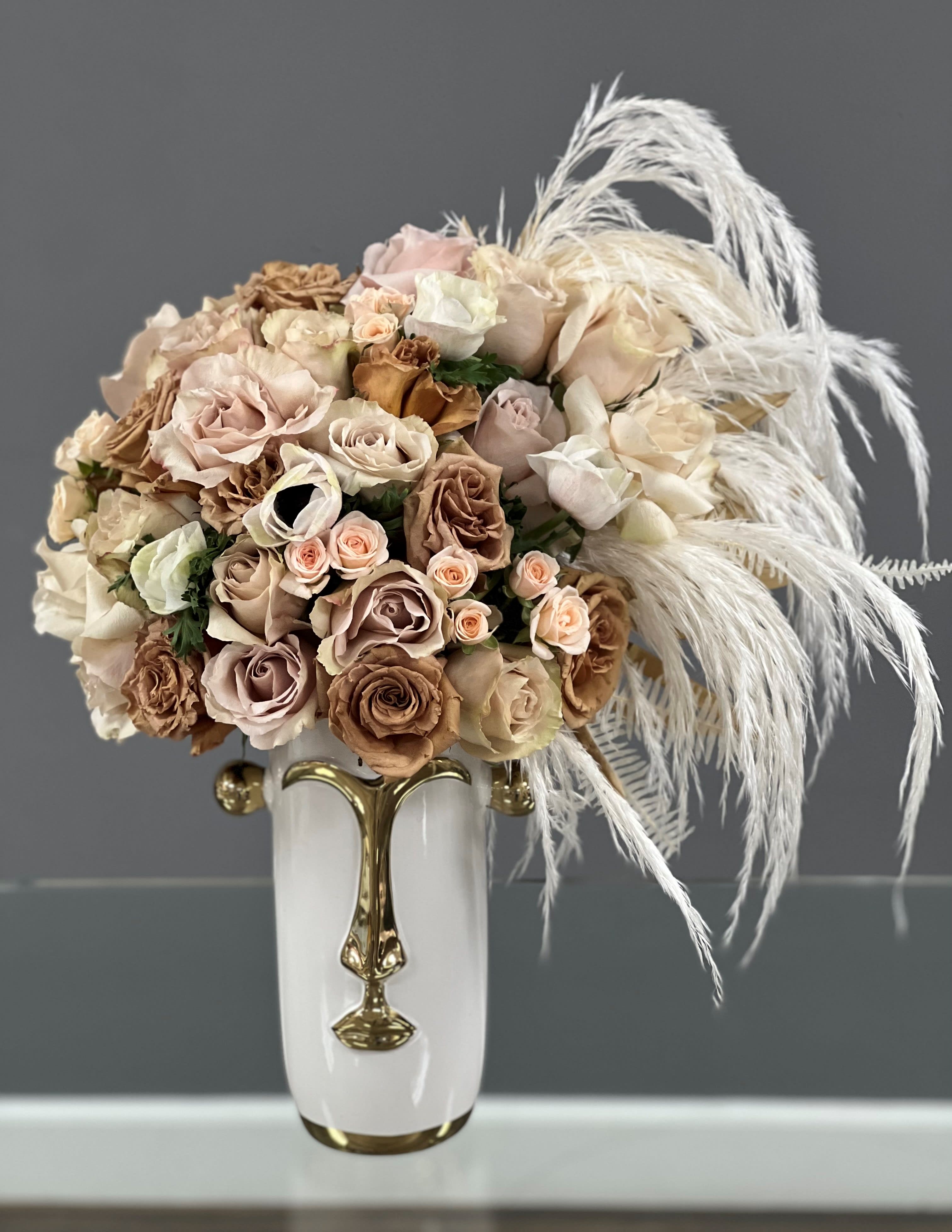 Bouquet of blush and beige roses in a white vase with white feathers