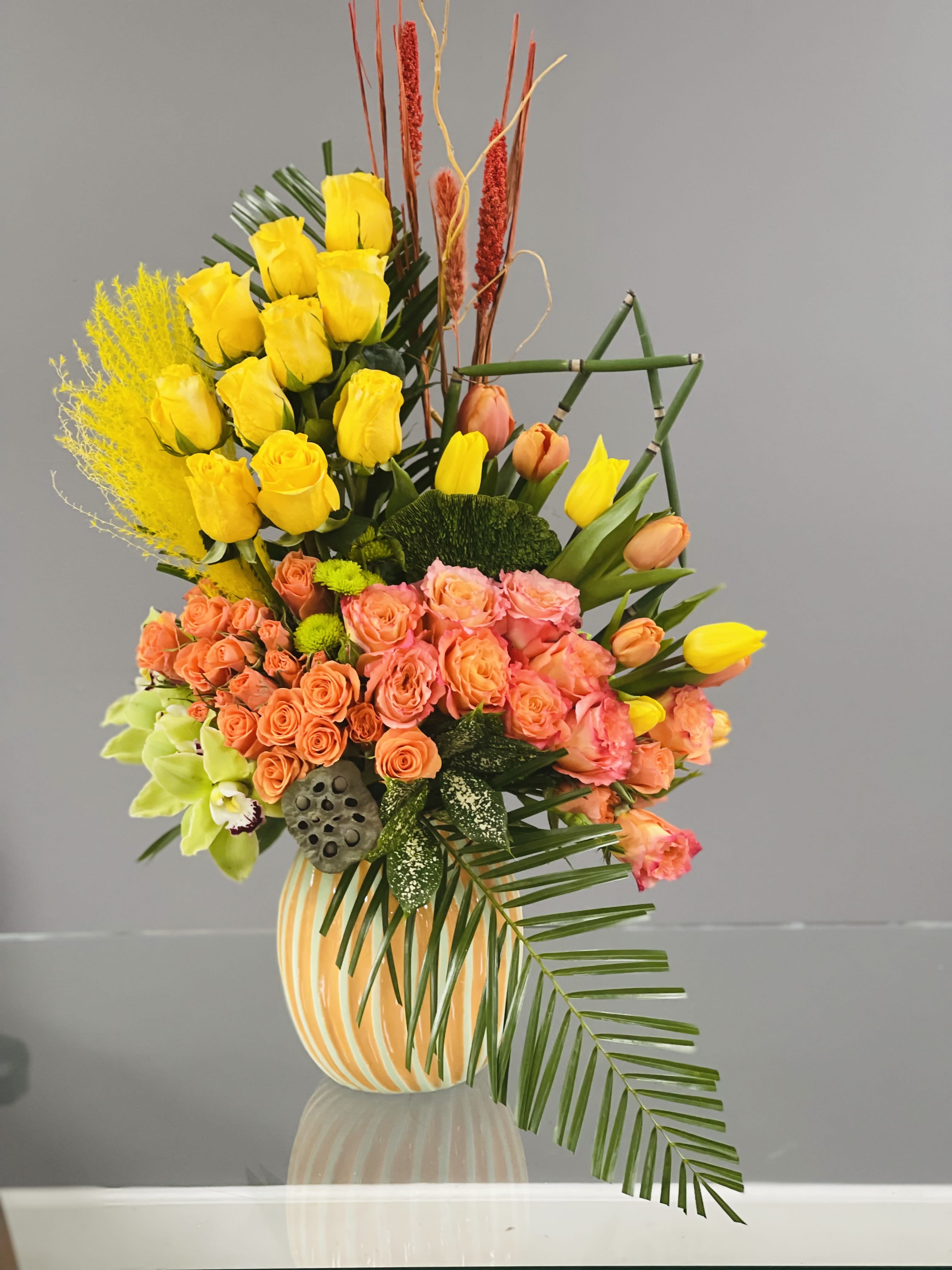 Mixed bouquet of yellow and peach flowers in a striped vase