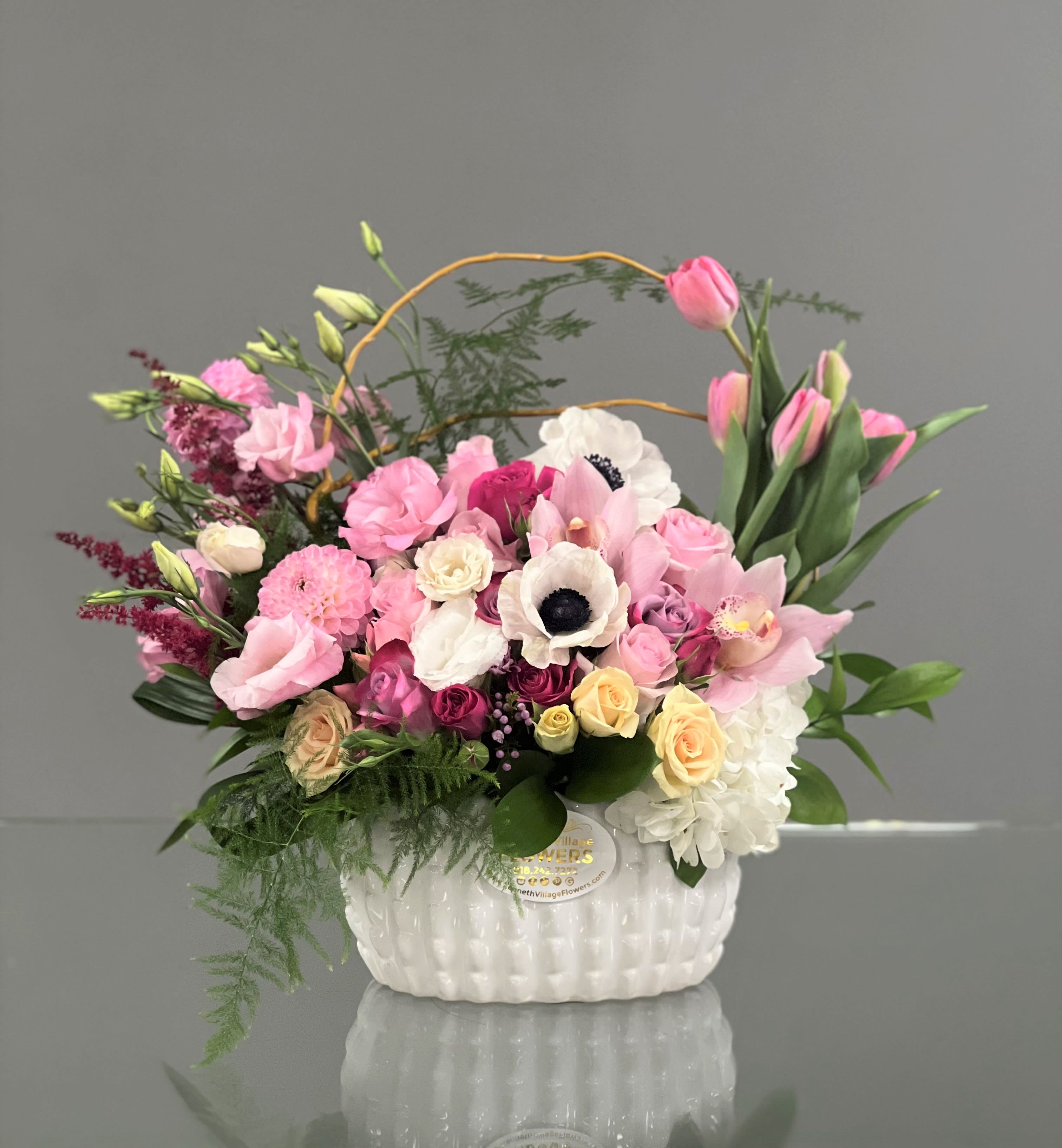 Pink and white mixed flower arrangement in a white basket vase