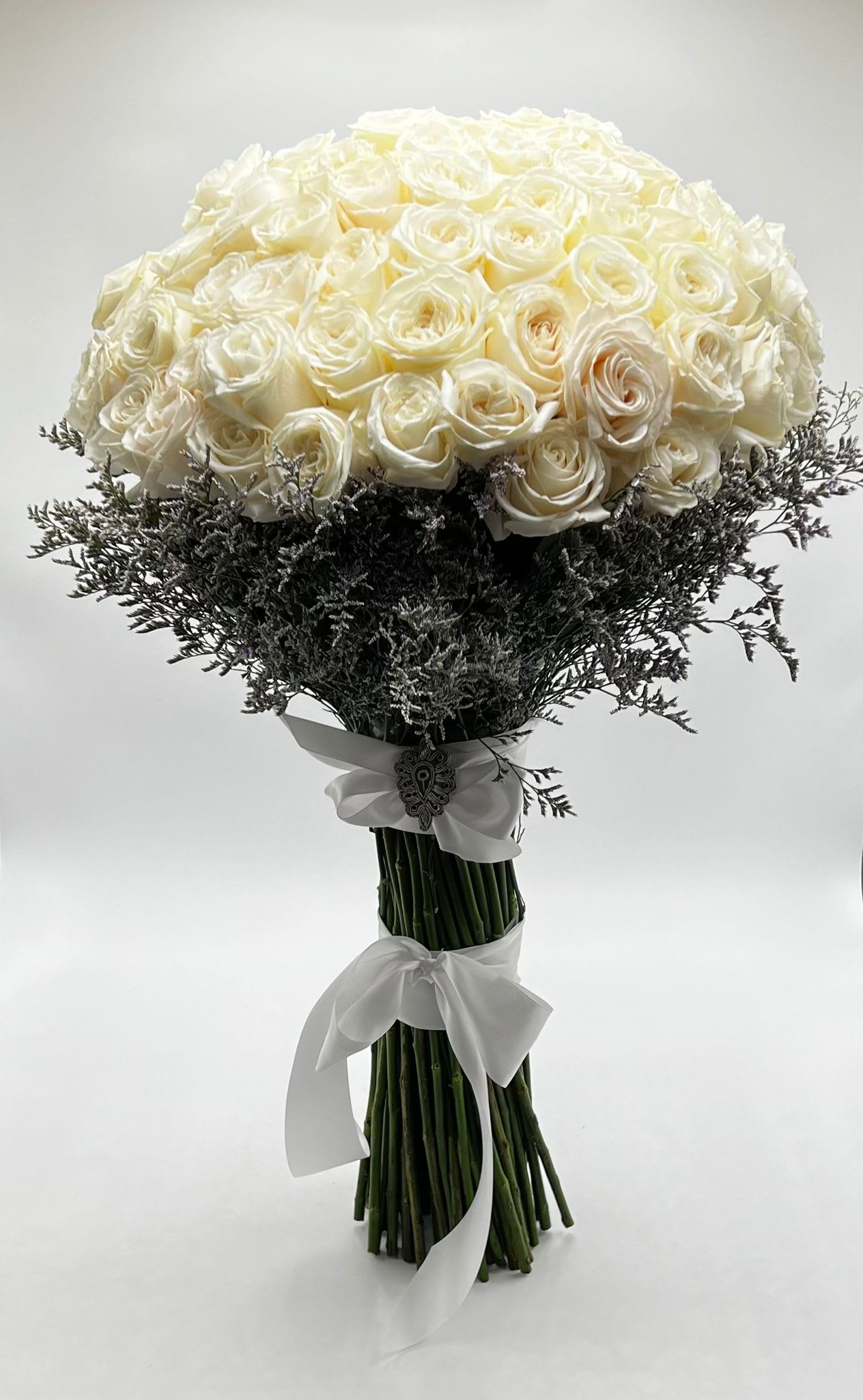 Bouquet of white roses with dark filler and white ribbon