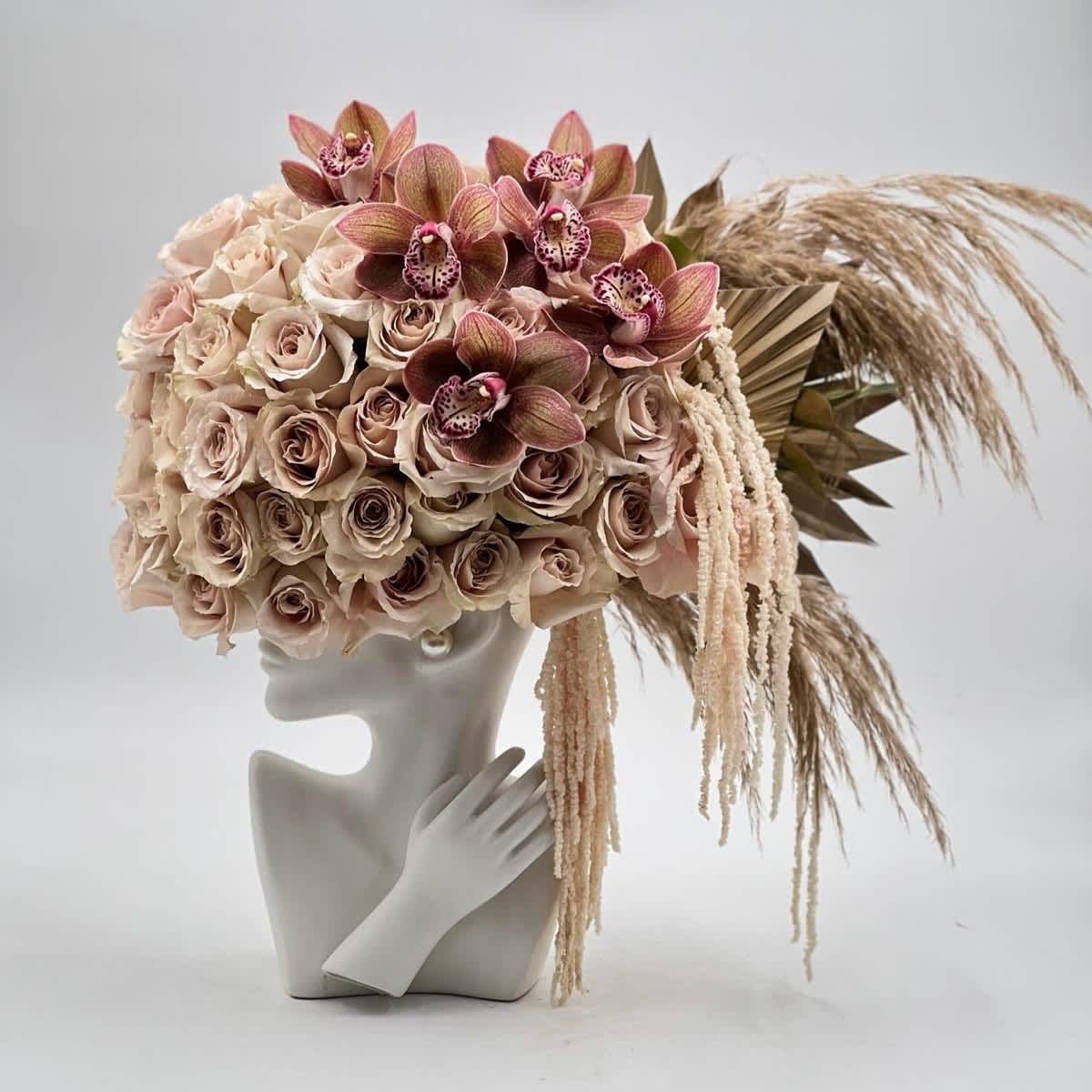 Blush rose and orchid arrangement on a mannequin bust with dried grasses