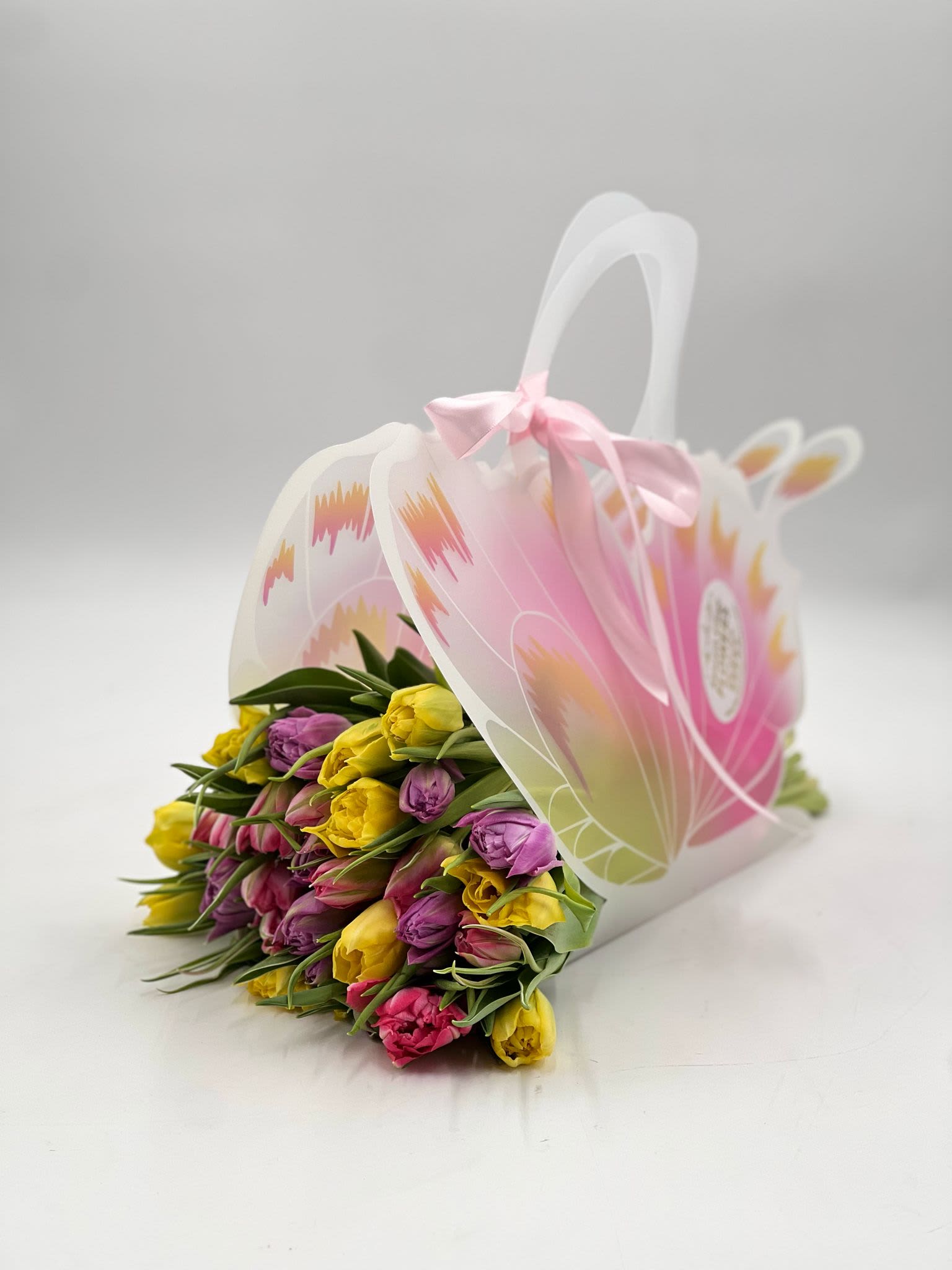 Bouquet of pink, yellow, and purple tulips in a decorative gift bag