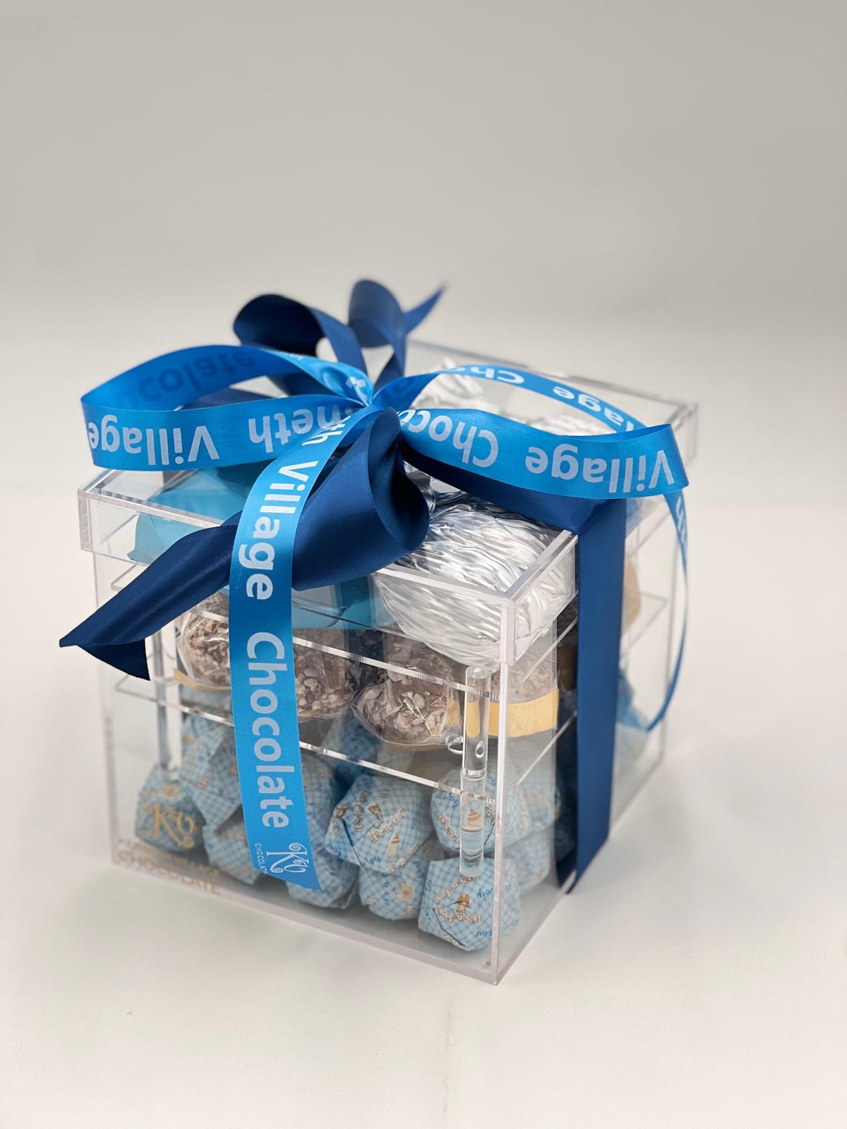 Clear gift box filled with assorted chocolates and tied with a blue ribbon