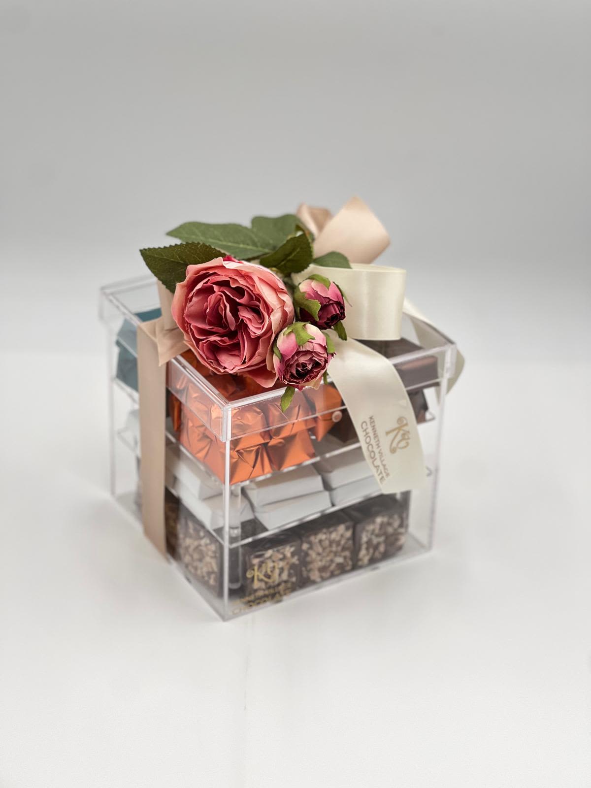 Gift box topped with pink roses and ribbon