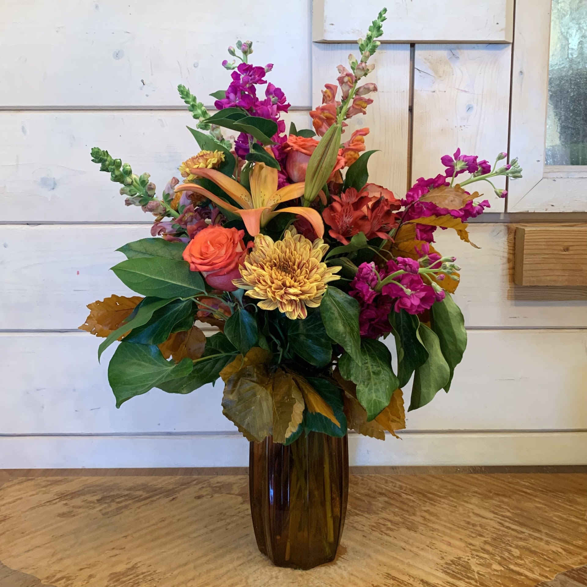 Colorful mixed flower arrangement in a tall brown vase