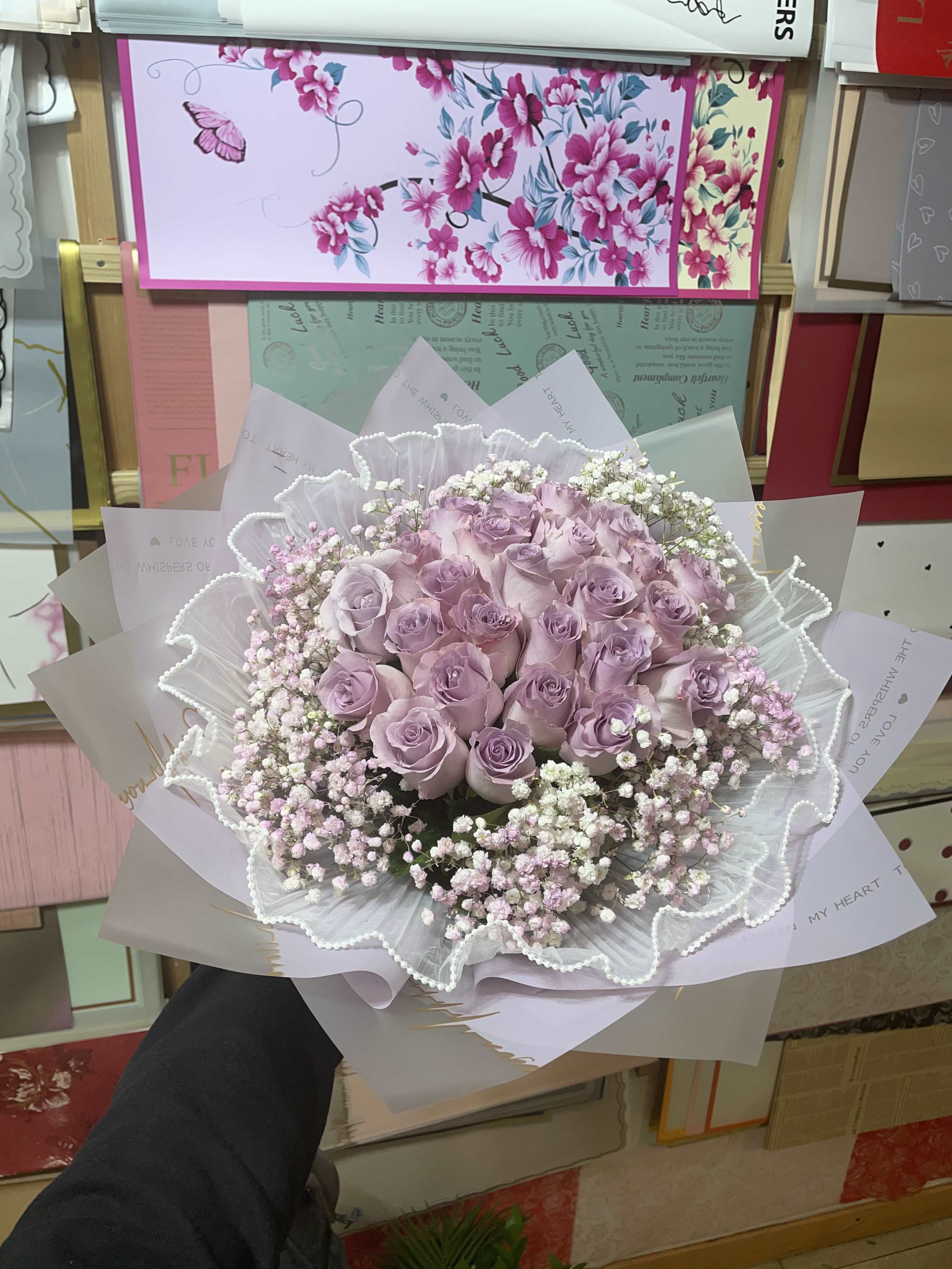 Lavender rose bouquet wrapped in white paper with baby's breath