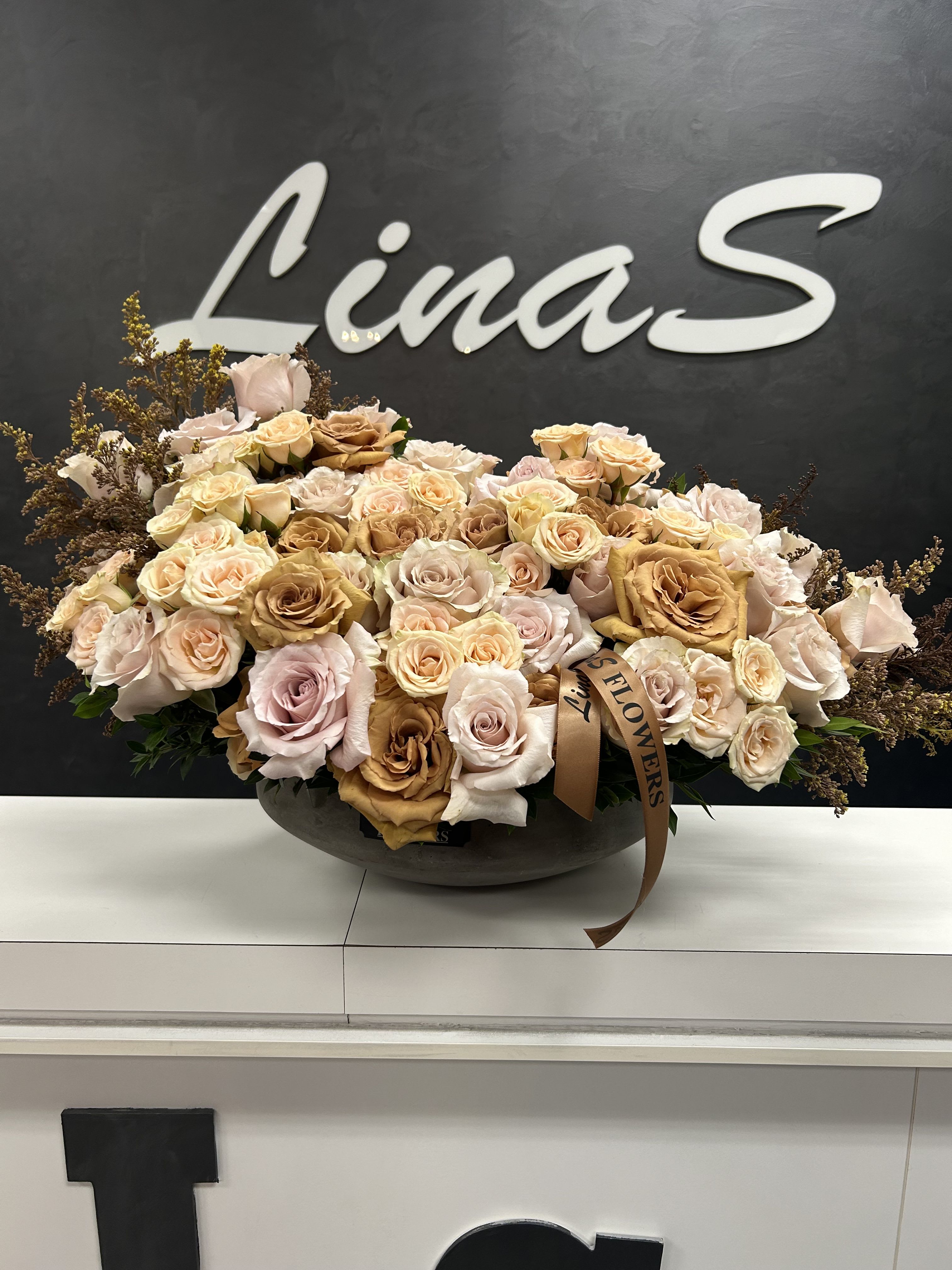 Large bouquet of pale roses in a low dark bowl