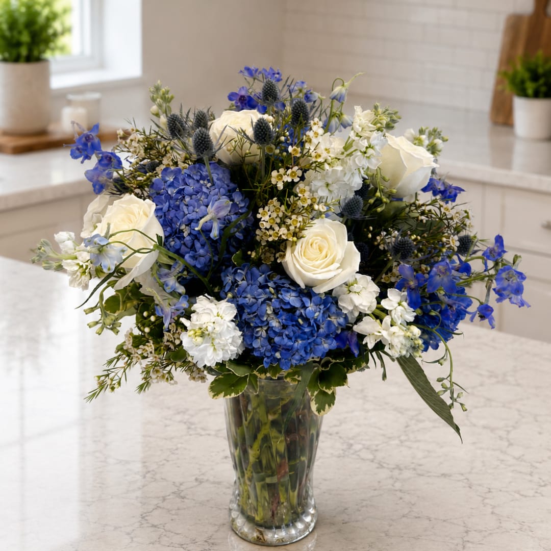 Blue and white flower arrangement in a clear glass vase