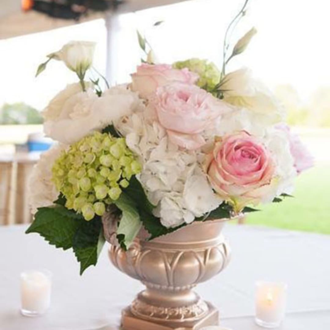Pink and white roses in a decorative vase with hydrangea accents