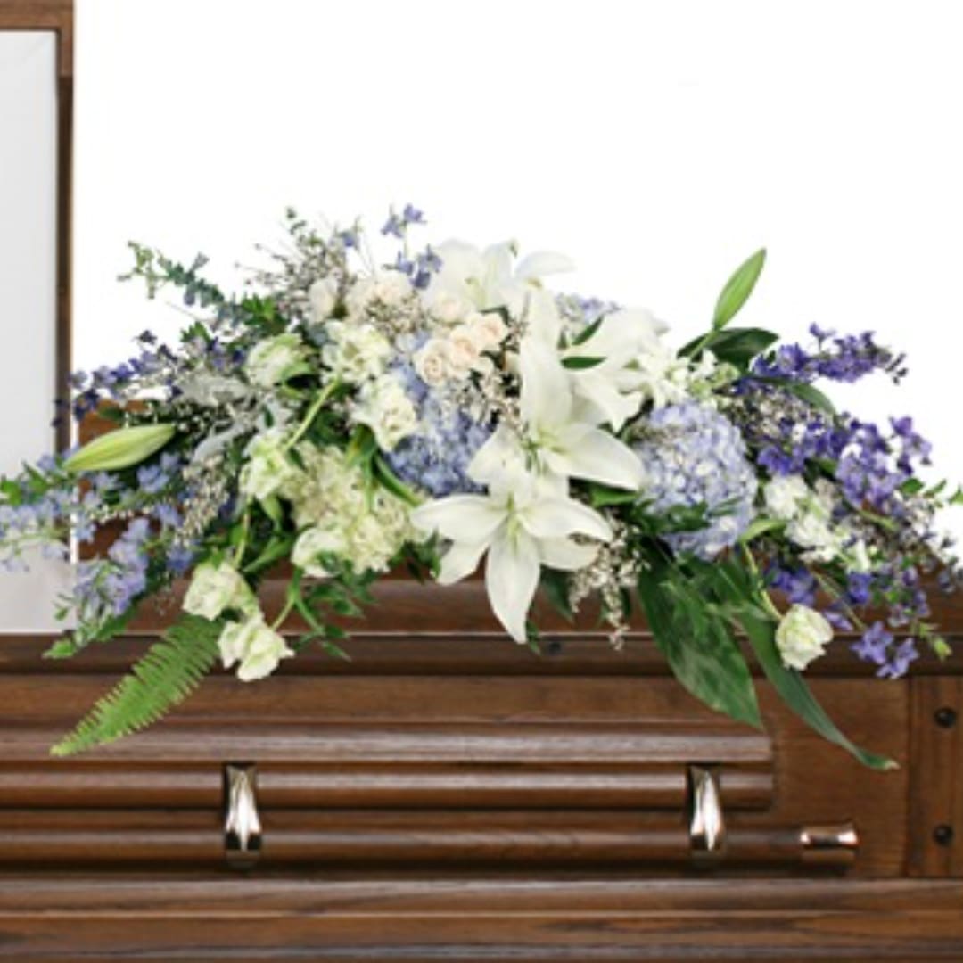 White and lavender floral spray on a wooden casket