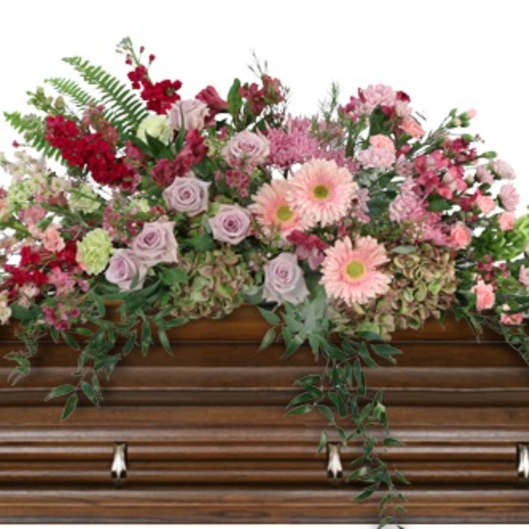 Pink and red floral arrangement on a wooden casket