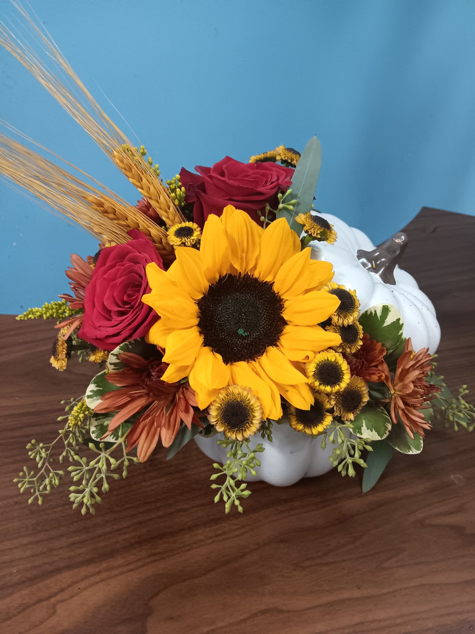 Sunflower and rose arrangement in a white pumpkin container
