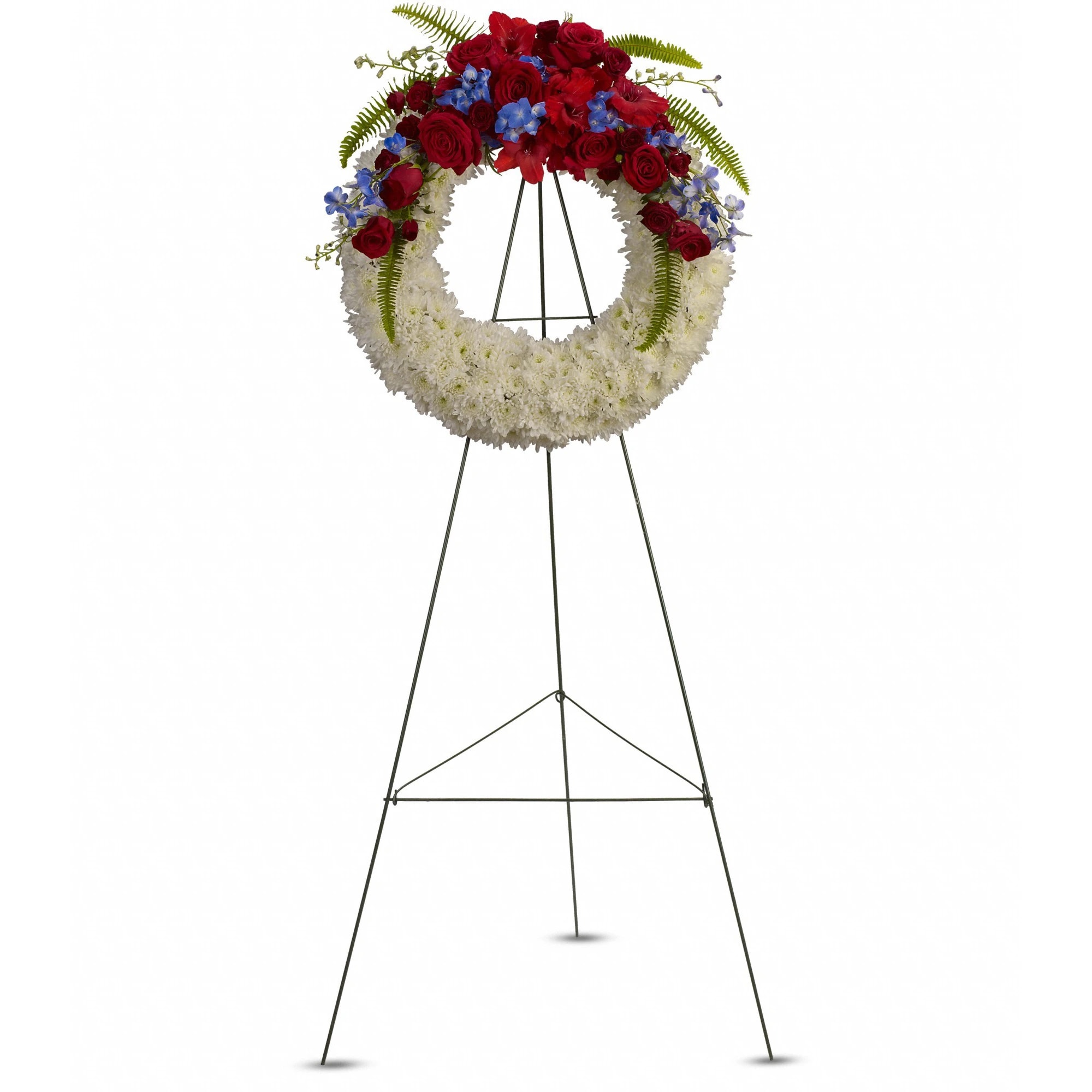 Patriotic standing wreath of white flowers with red roses and blue accents on a metal easel