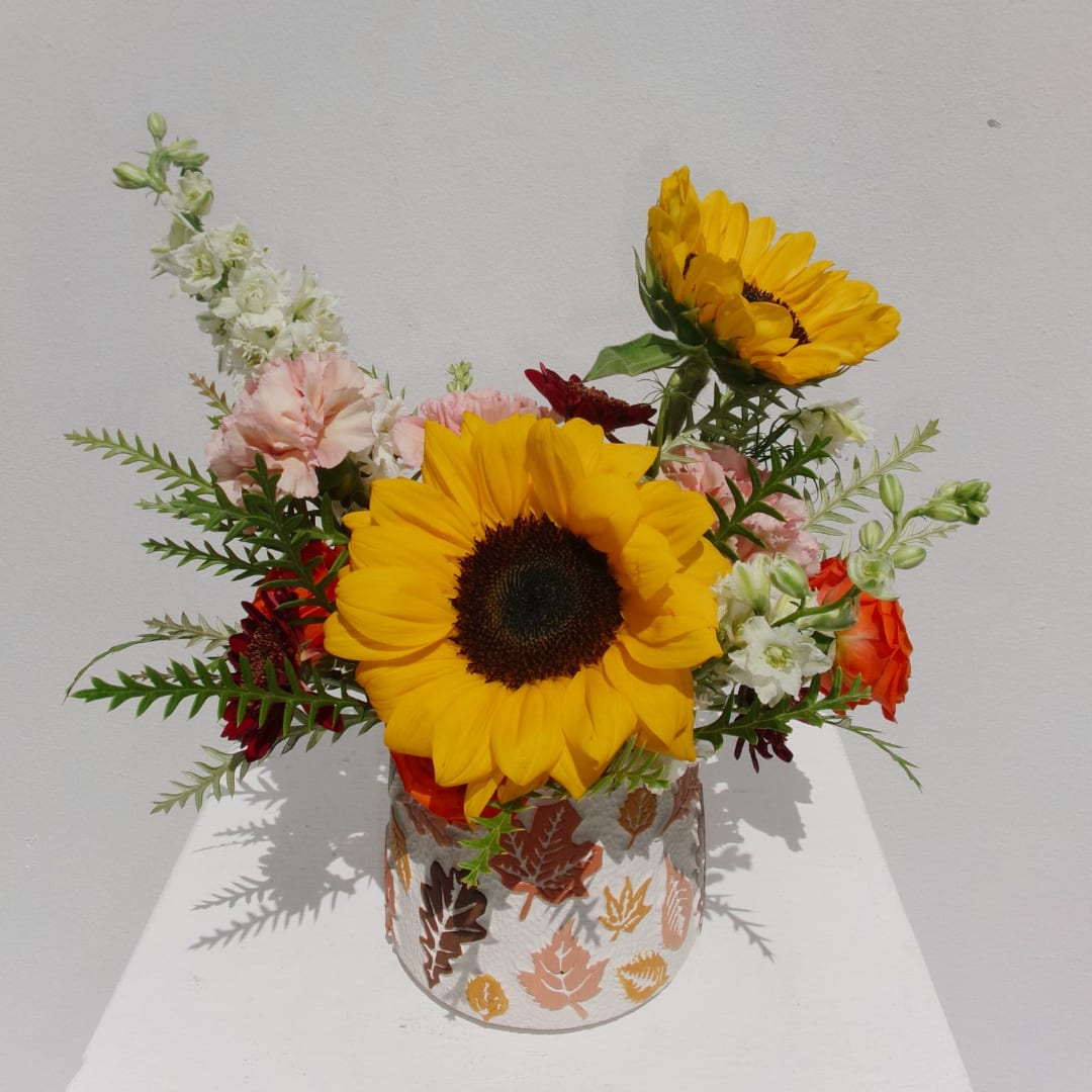 Sunflowers and mixed blooms arranged in a patterned vase