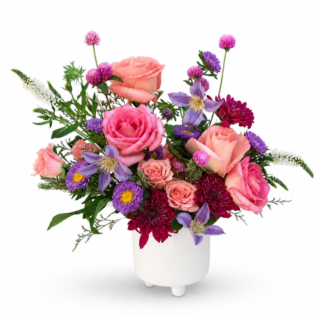 Pink and purple mixed flower arrangement in a white vase
