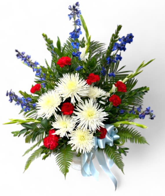 Red and white flowers in a white vase with a blue ribbon