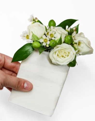 White floral corsage with green accents on a white card