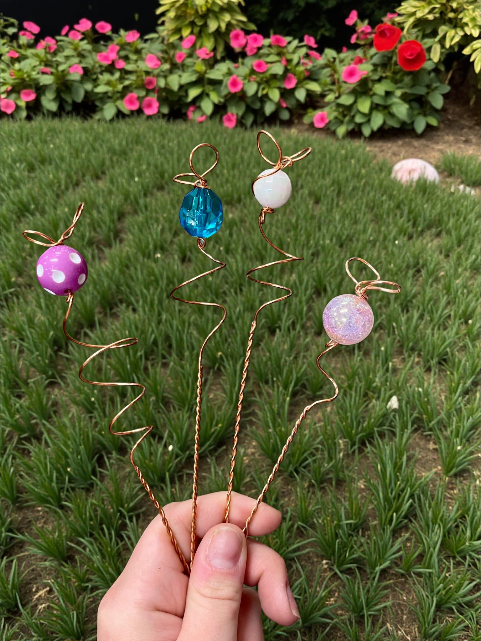 Hand holding four wire flower picks with colorful beads