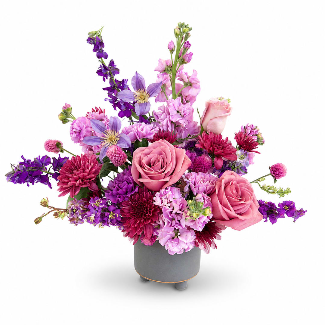 Pink and purple mixed flower arrangement in a gray vase