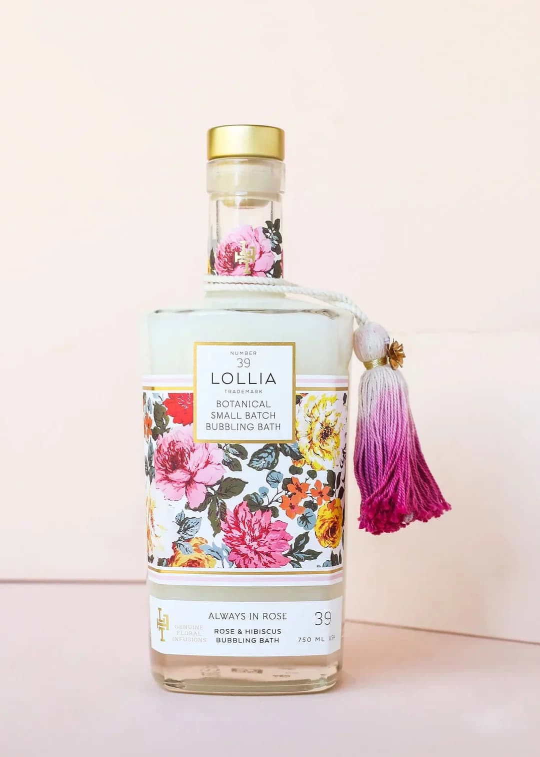 Floral-patterned bath bottle with a pink tassel and gold cap