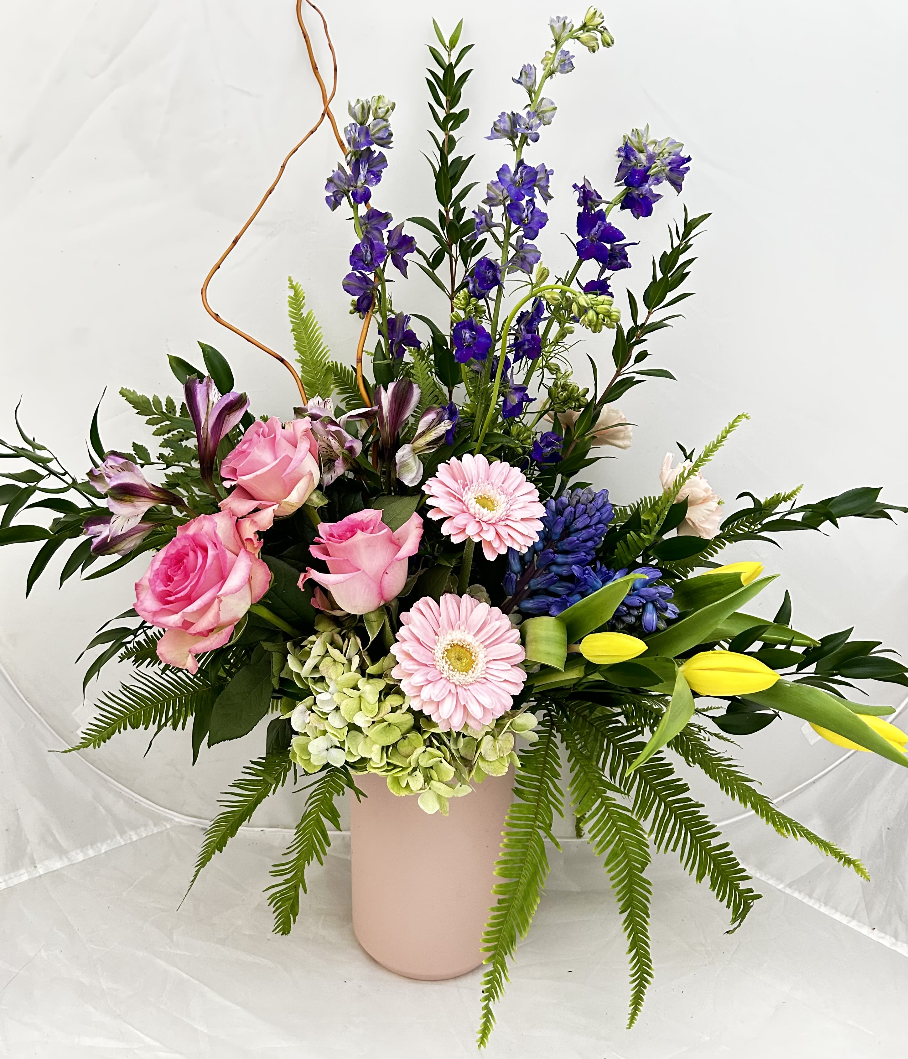 Mixed bouquet of pink roses, lilies, and purple flowers in a pink vase