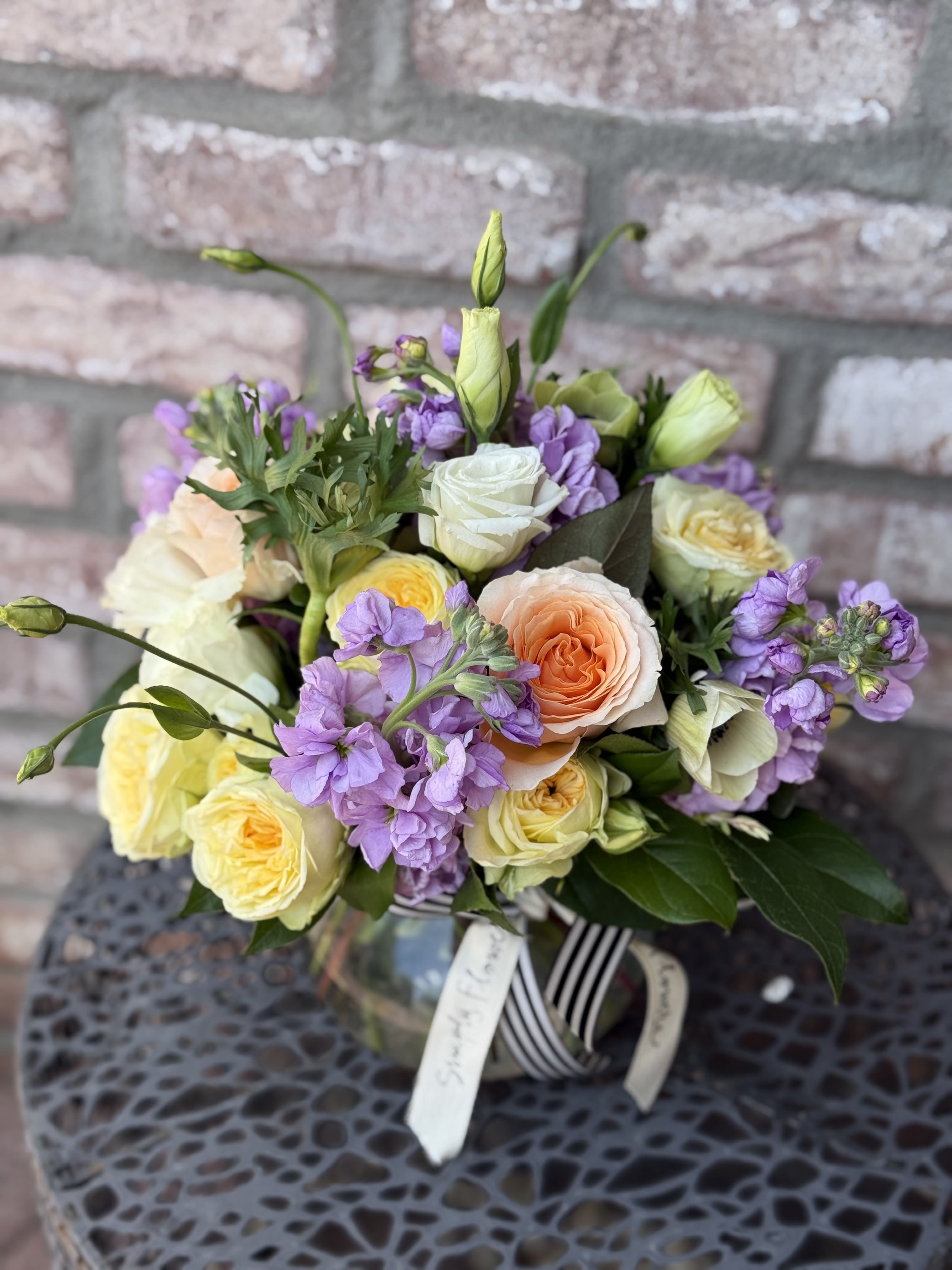 Bouquet of peach, white, and yellow roses with purple flowers